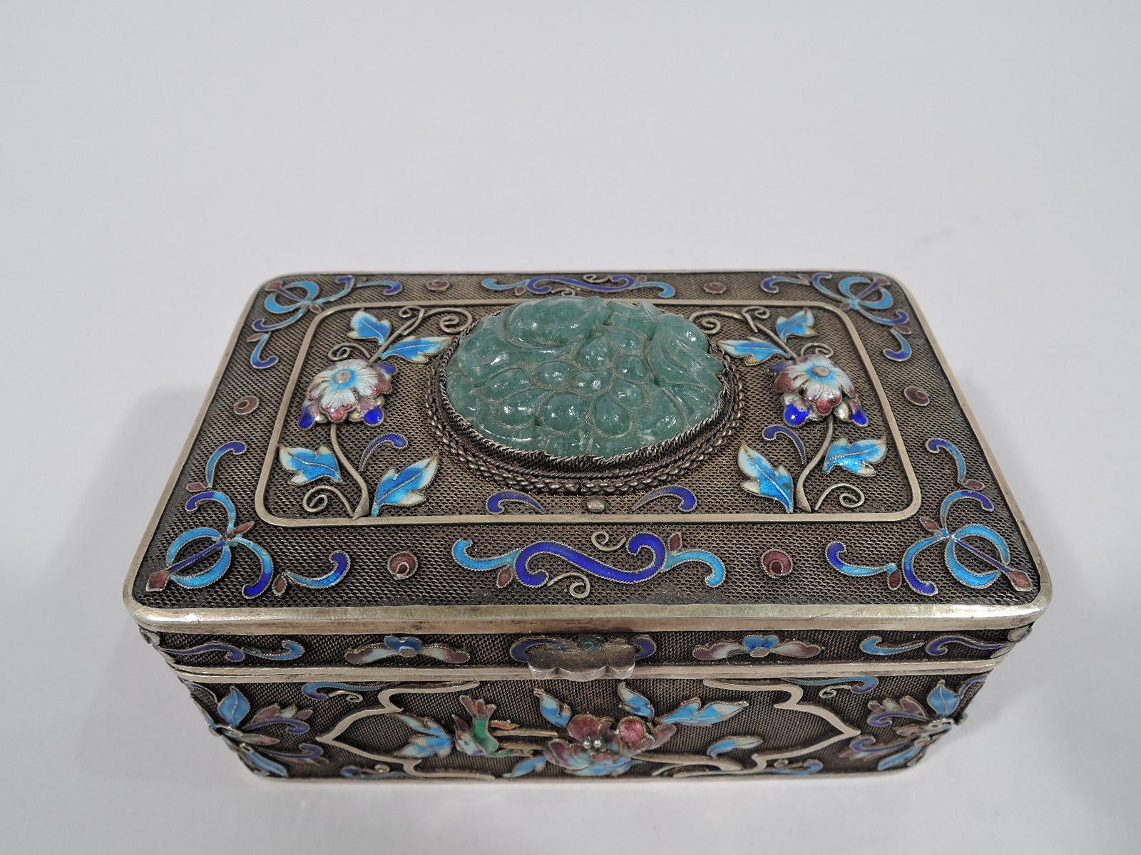 Chinese silver gilt filigree box with enamel and carved jade, ca 1910. Rectangular with curved corners and hinged cover with scrolled tab. Enamel scrolls and flowers in shades of blue, green, pink, and white applied to mesh ground. Cover has cabled