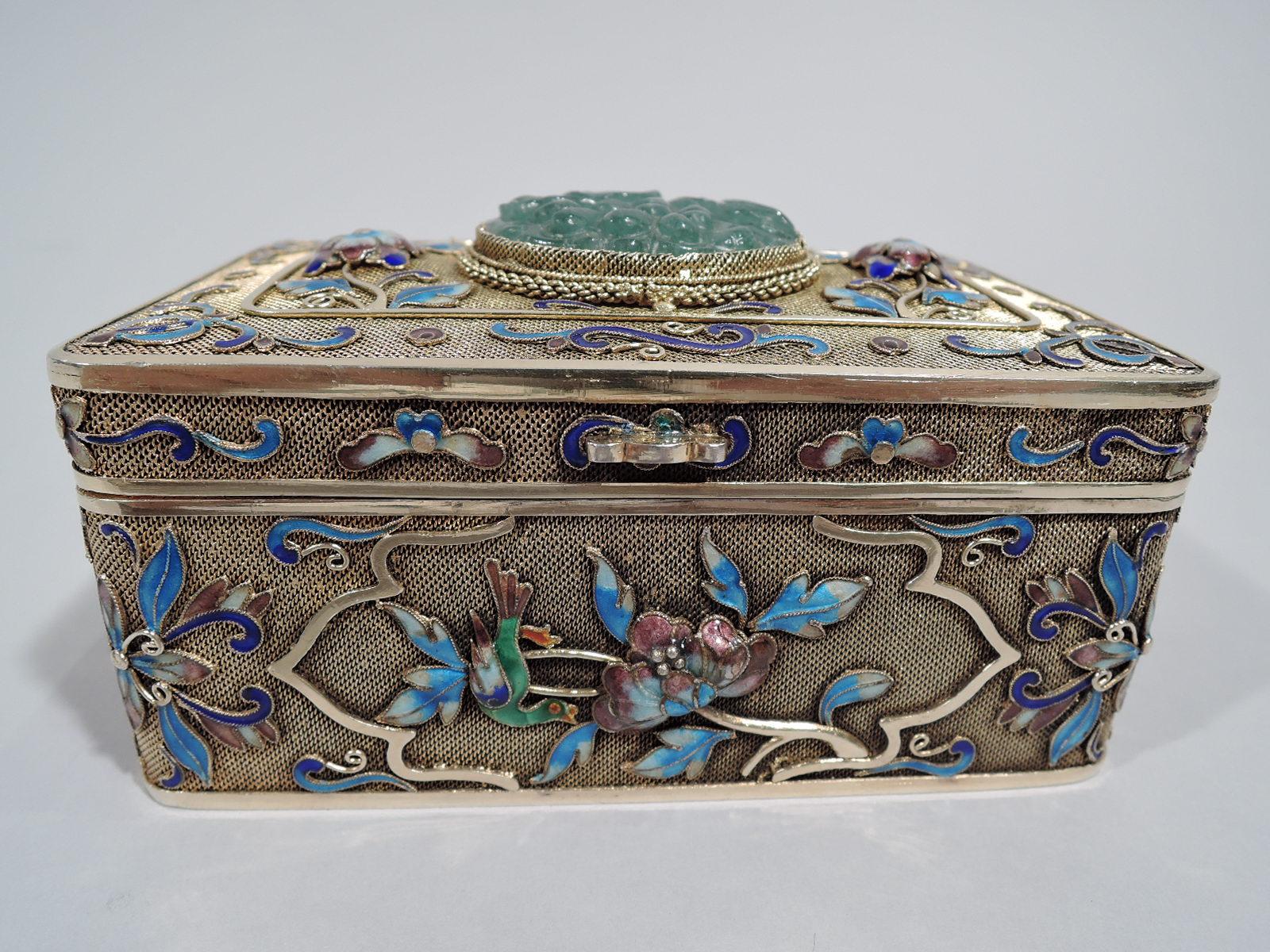 Chinese silver gilt filigree box with enamel and carved jade, ca 1910. Rectangular with curved corners and hinged cover with scrolled tab. Enamel scrolls and flowers in shades of blue, green, pink, and white applied to mesh ground. Cover has cabled