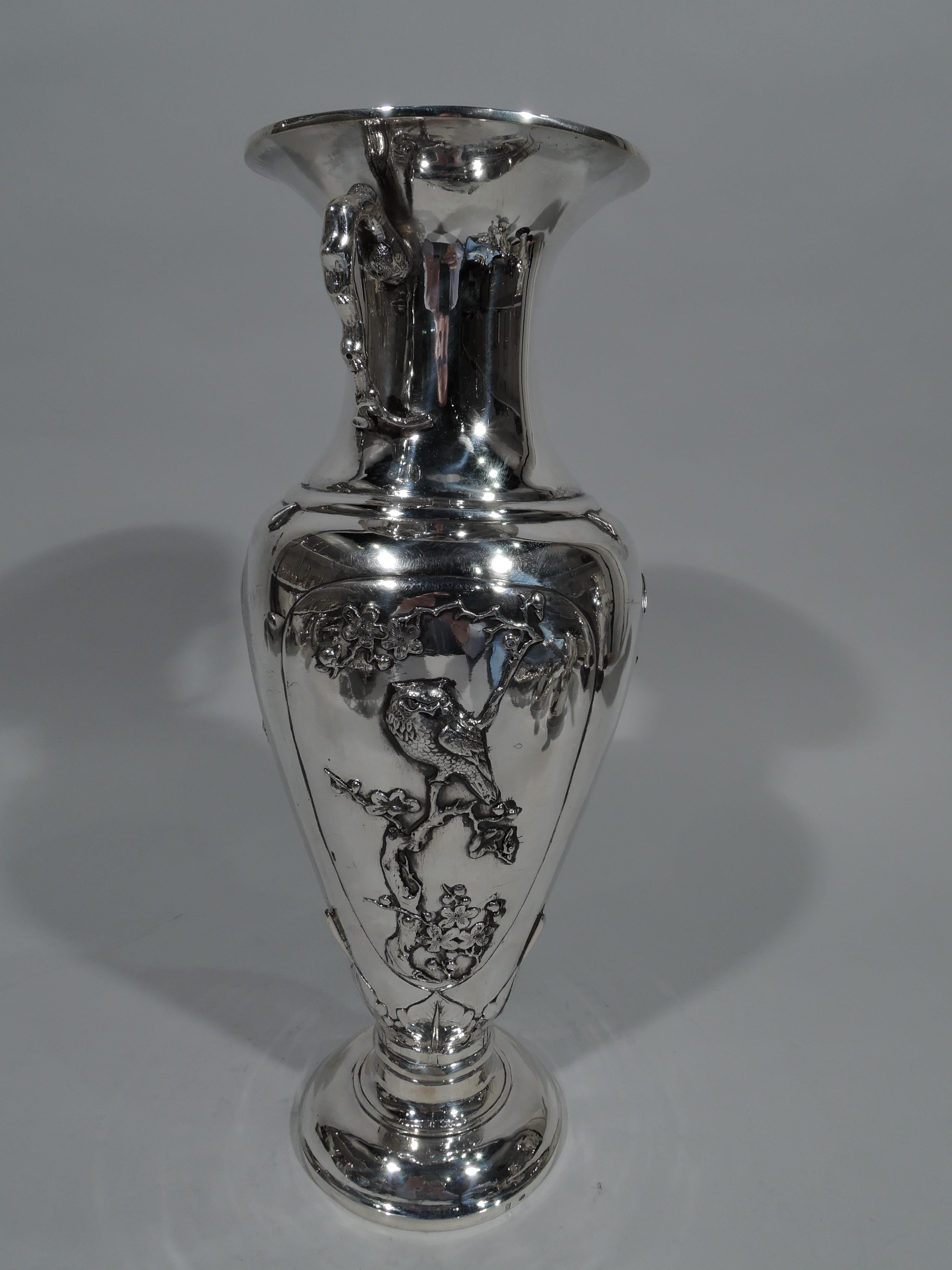 Chinese silver vase, circa 1900. Classical Amphora with domed foot, concave neck, and flared mouth. Branch-style scroll handles mounted to neck. Oval frames with bamboo, blossoming prunus branches, and perched birds including one severe owl.