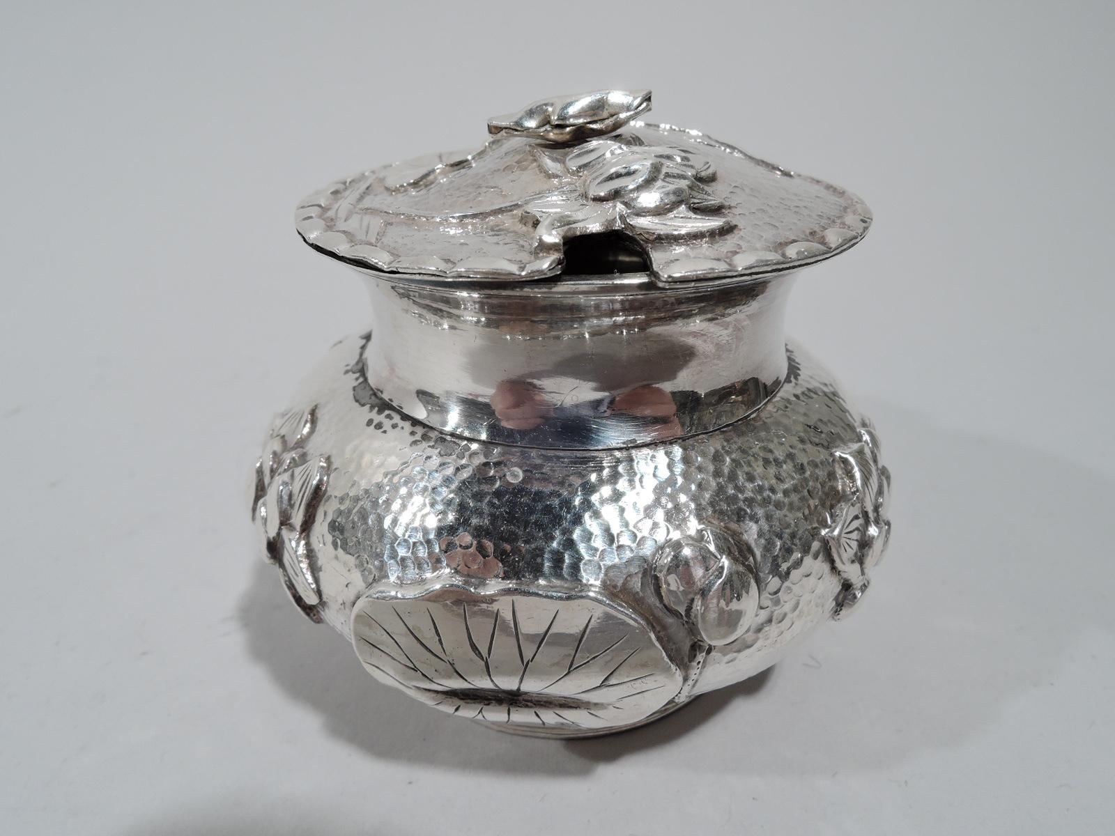 Turn-of-the-century Chinese silver mustard pot. Round and bellied bowl with plain concave neck, thin scroll handle, and spread foot. Modish floral ornament in form of chased and applied water lilies and pads heightened with engraving on stippled
