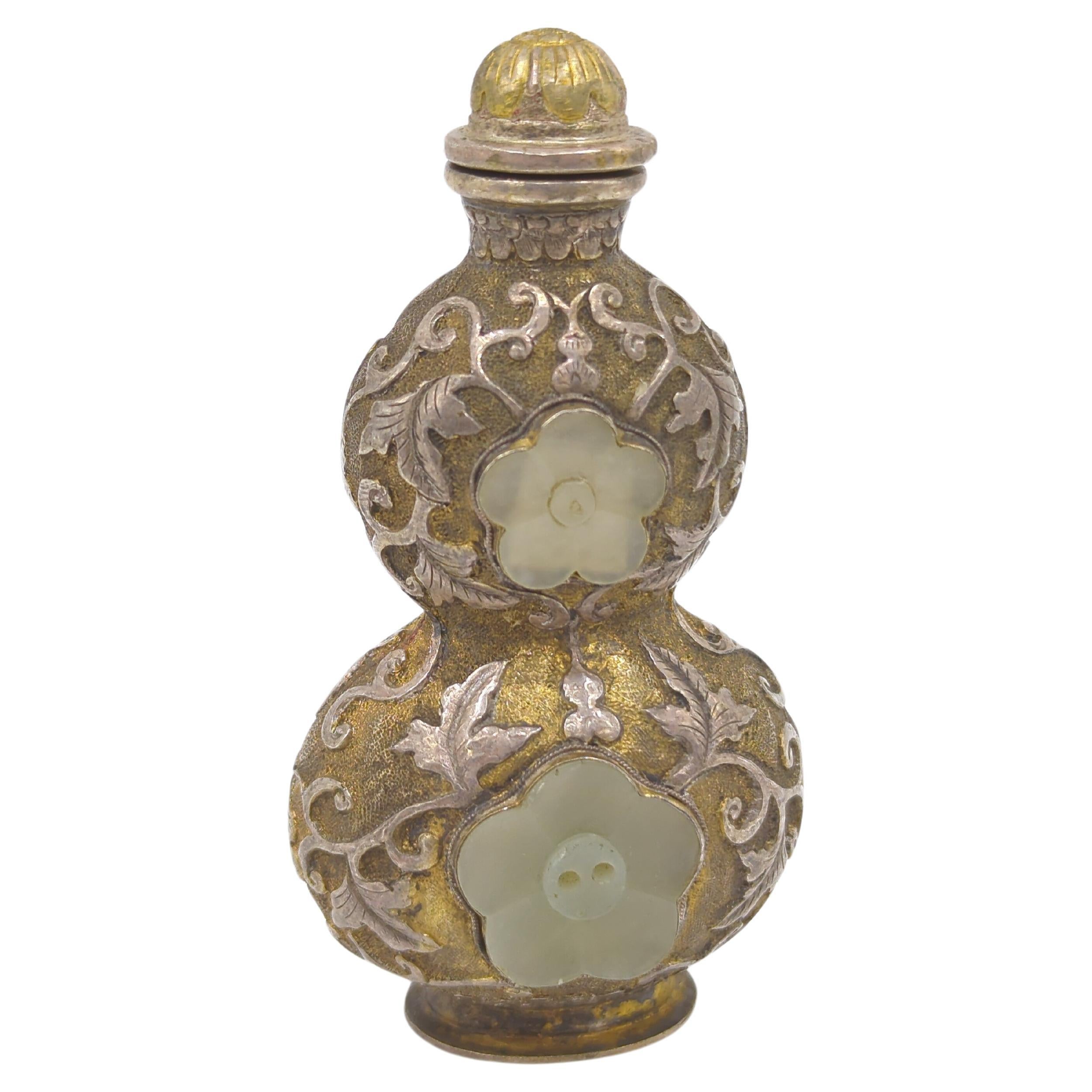 Fine antique Chinese Qing Dynasty silvered golden copper alloy snuff bottle of hulu double gourd form, inset with 4x carved five petal white jade plum flowers, body decorated with scrolling foliage and ruyi head border in relief above the raised