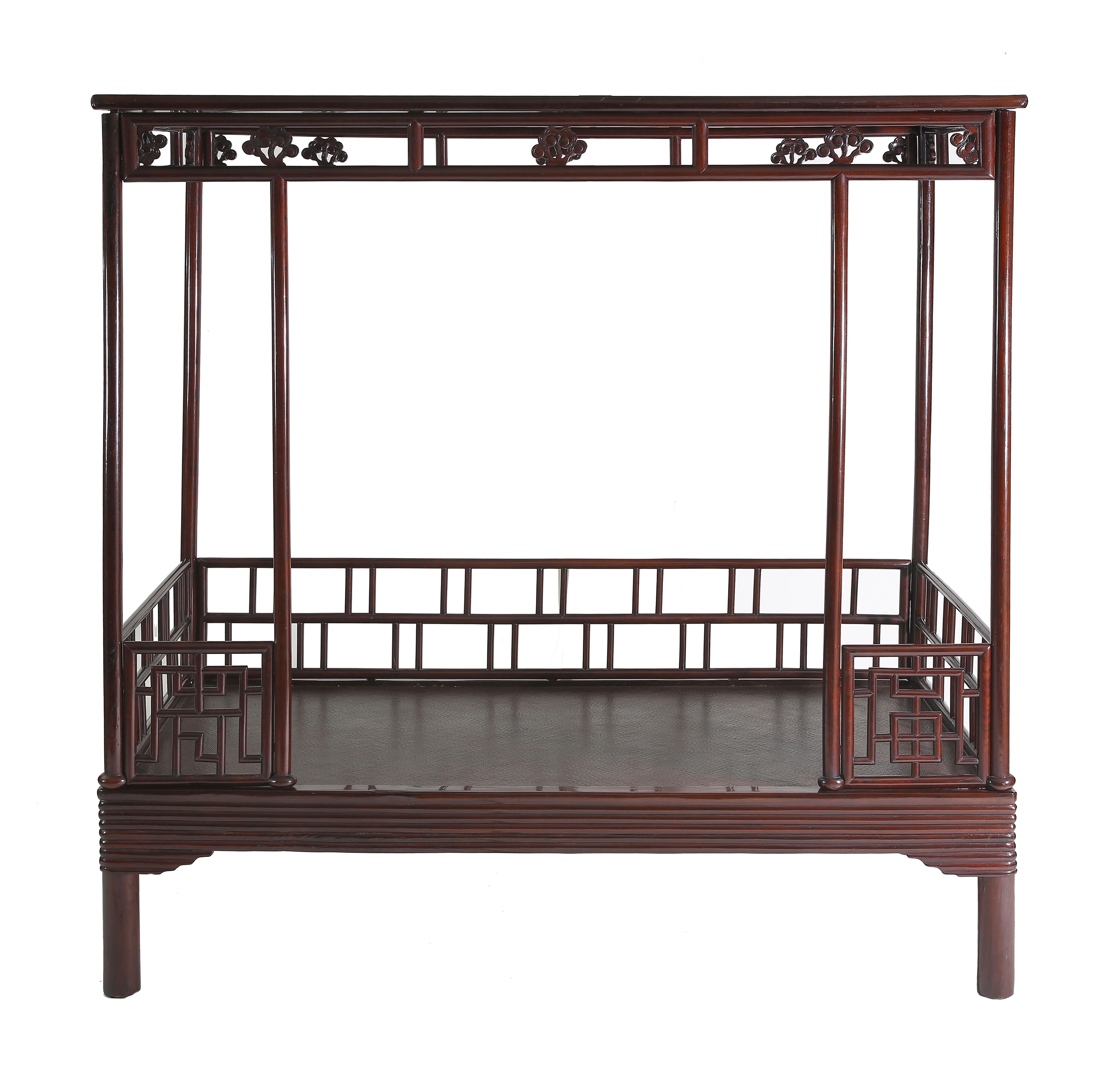 The bed bse frame enclosing a cane top and decorated with wrapped-around lipped molded edges and spandrels, supported on circular-sectioned legs; the six posts braced on the back and sides by railings of fretwork, two short railings flanking the