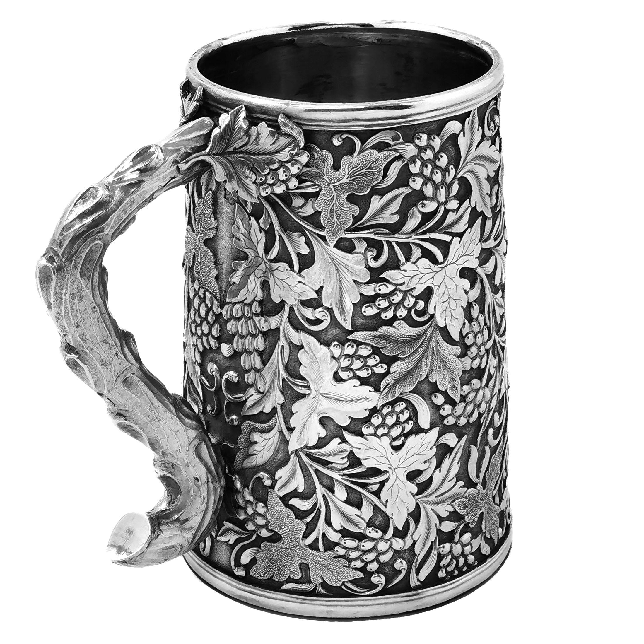 A beautiful Antique Chinese solid Silver Mug showing an ornate grape, vine & leaf design wrapped around the entire body of the Tankard. The Tankard has an impressive vine shaped handle and a blank shield shaped cartouche opposite the handle. 

Made
