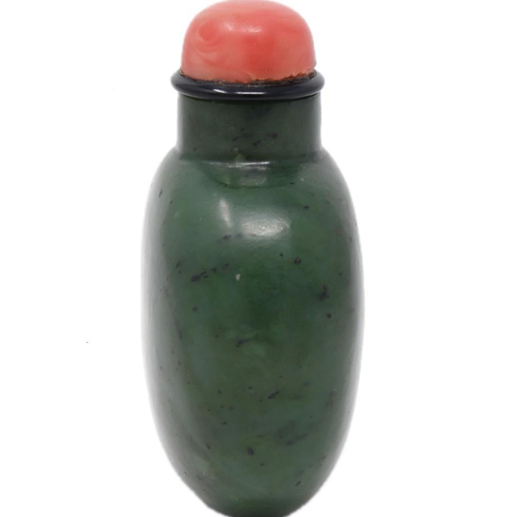 Bouteille à priser en jade épinard, dynastie Qing. La forme ovoïde aplatie, symétriquement rendue à partir d'une pierre de néphrite cireuse mouchetée de vert d'épinard, présente une épaule haute et un col rond court et robuste, l'embouchure fraisée