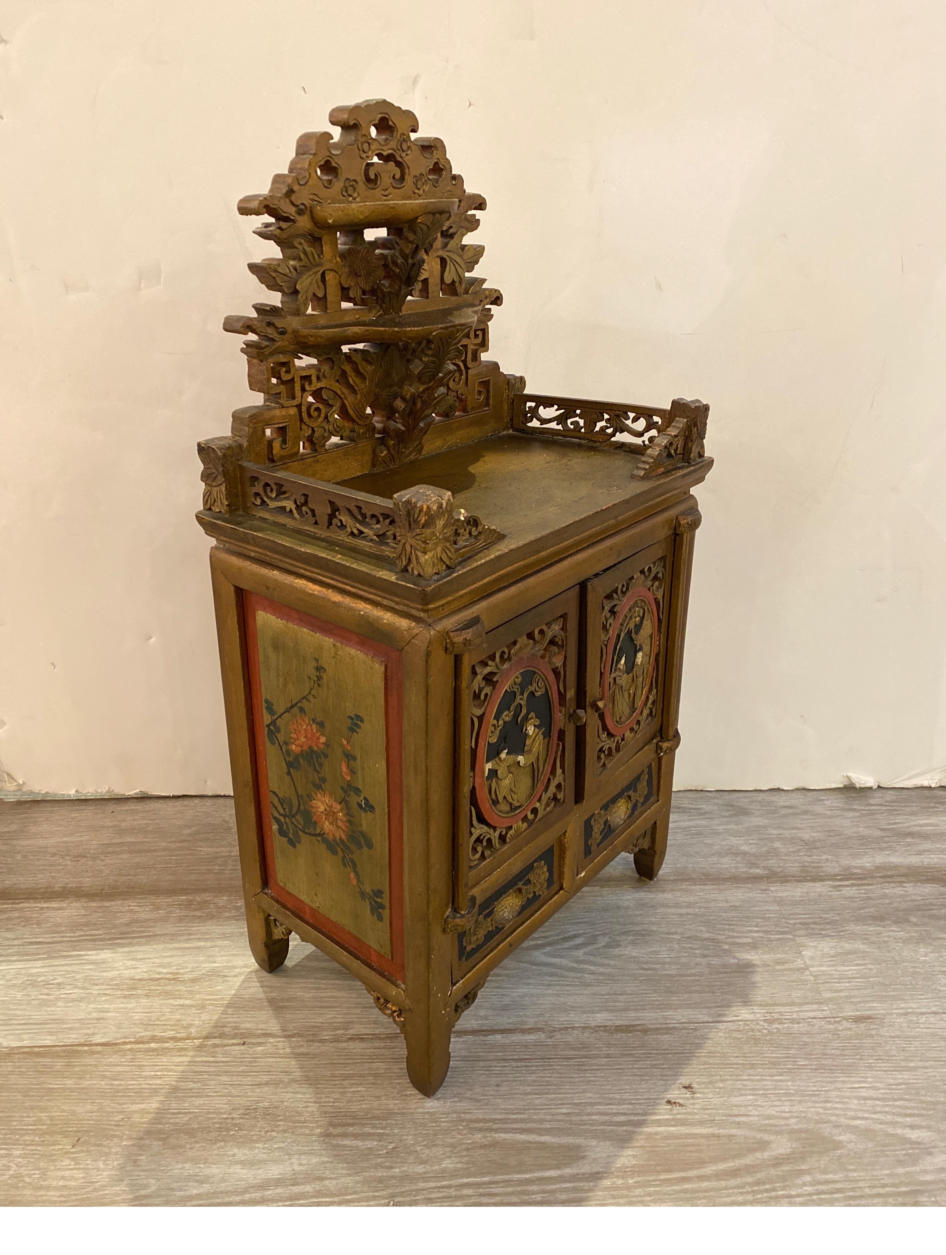 A small antique Chinese cabinet with hand carved and painted decoration. The top with 2 small shelves with two hand painted doors and drawers. The chest is 24.75 inches tall, 13 inches wide, 8 inches deep, would be prefect for jewelry or small