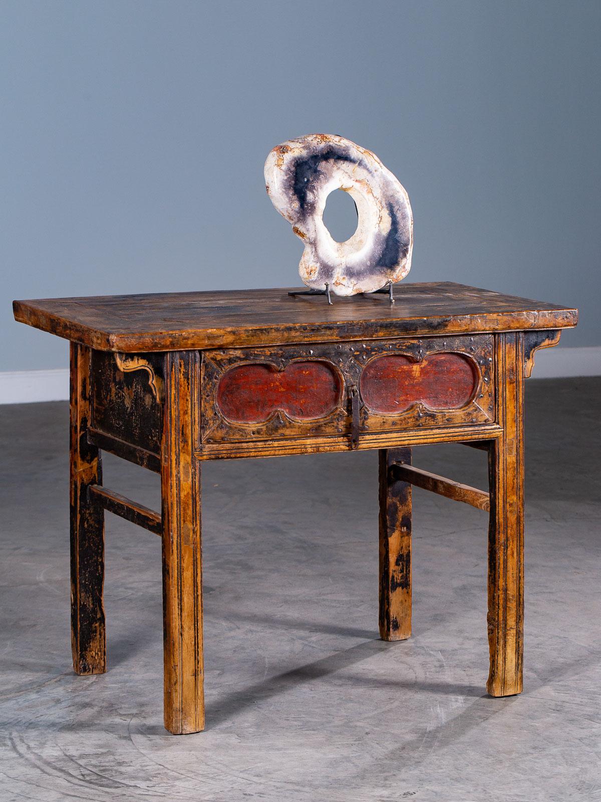 This good example of an antique Chinese table with a single wide drawer from Kuang Hsu period China, circa 1875 has a beautifully weathered surface still showing traces of the original lacquered finish in both black and red. The combination of color