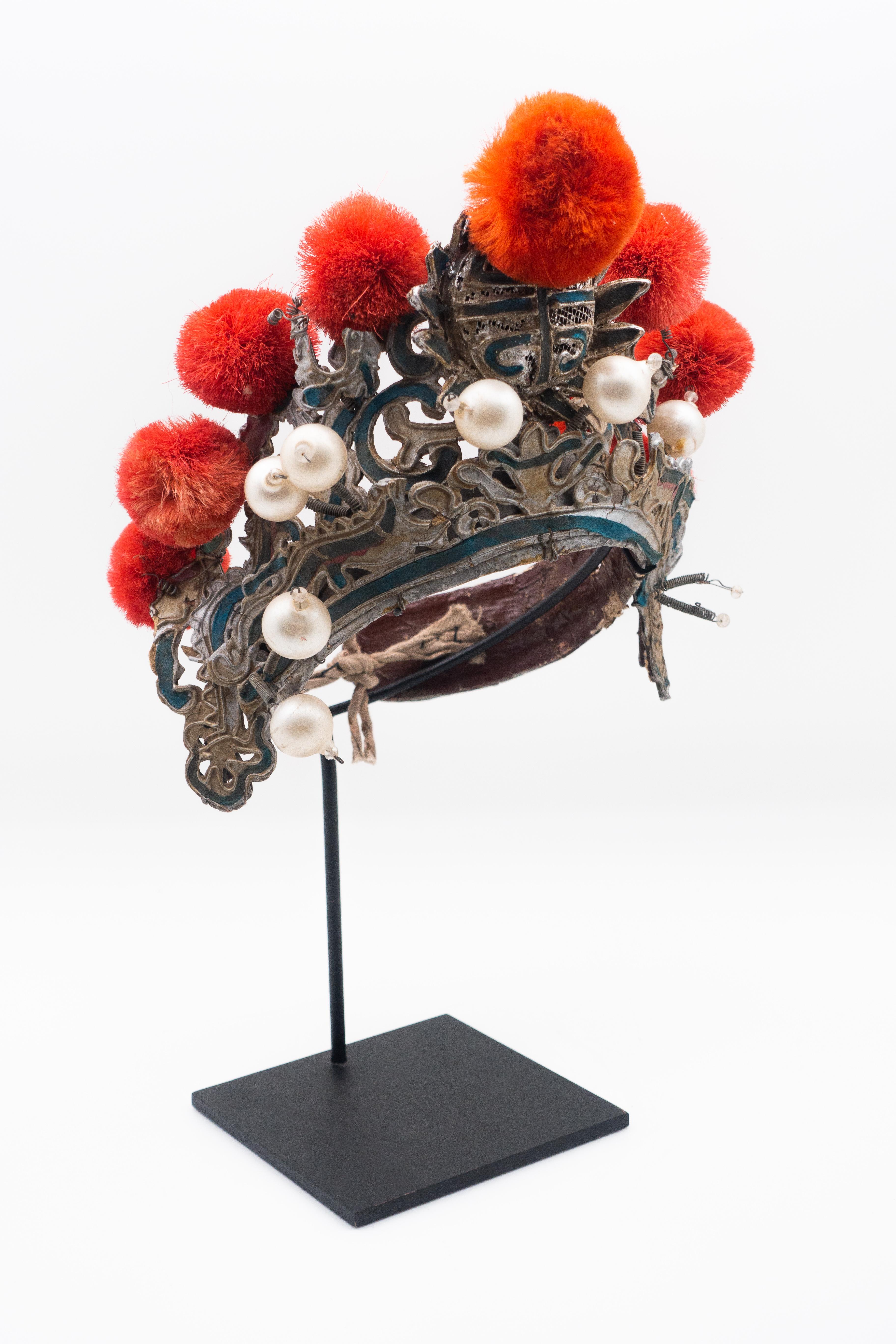Chinese opera theatre headdress in turquoise with coral colored pom poms along with faux pearls, early 20th century, mounted on a custom black painted metal base.