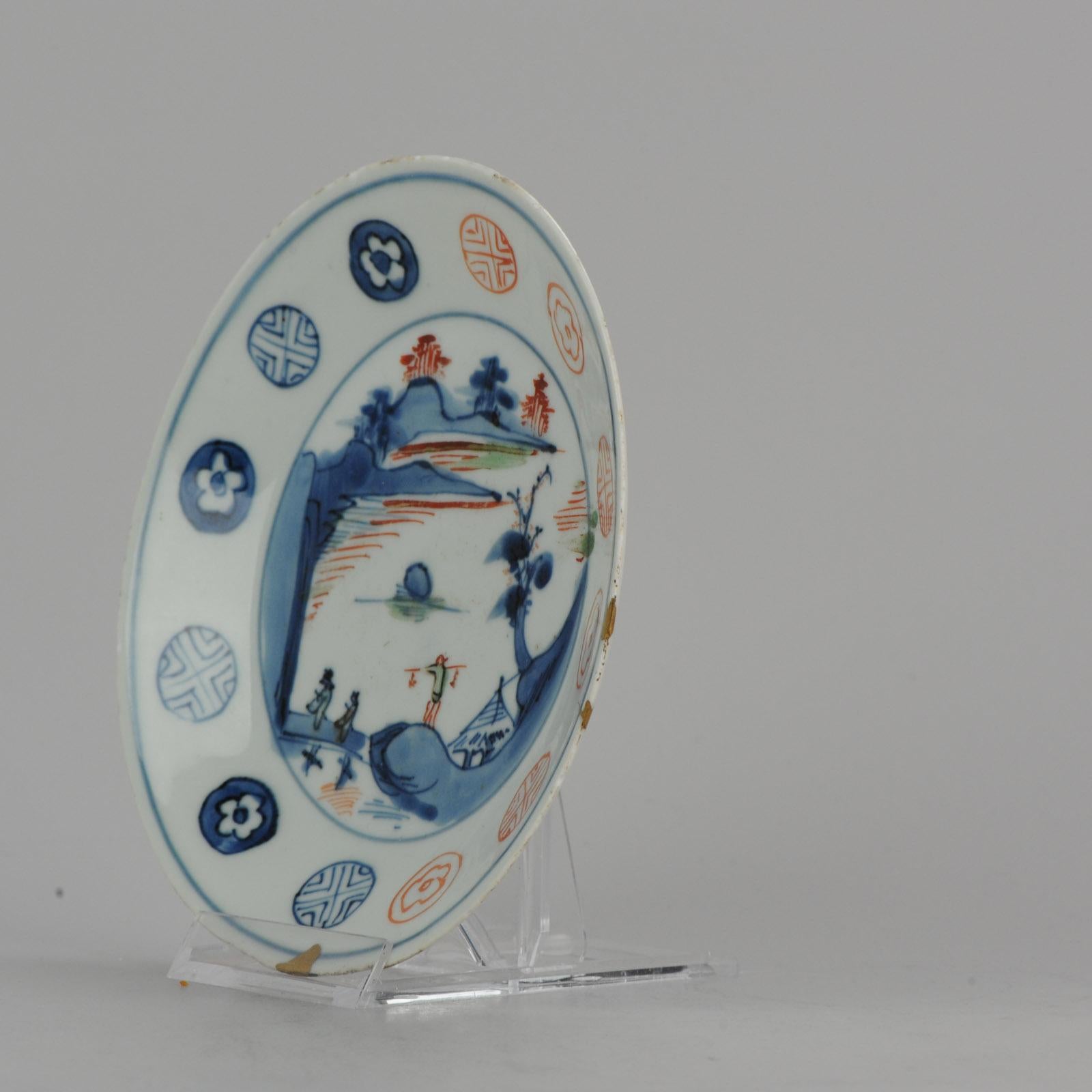 Dish of circular form with a shallow cavetto and everted rim, the center loosely painted with a scene of two scholars crossing a bridge away from a pavilion under a sheltering pine and towards a mountainous landscape, the border asymmetrical with