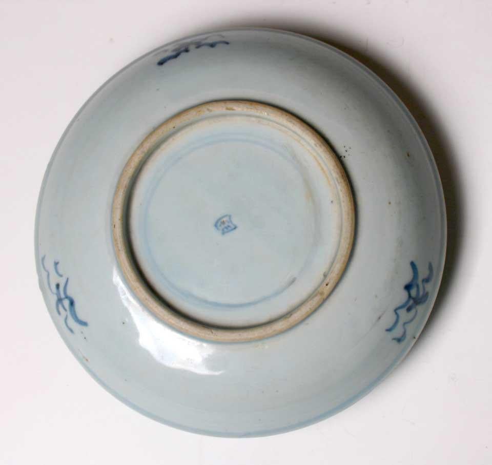 Antique Chinese “Transitional” ware blue and white plate, decorated in under glaze cobalt blue of a scholar seated in a garden on center surrounded by a few concentric bands, the underside with three wavy spots and some concentric bands around the