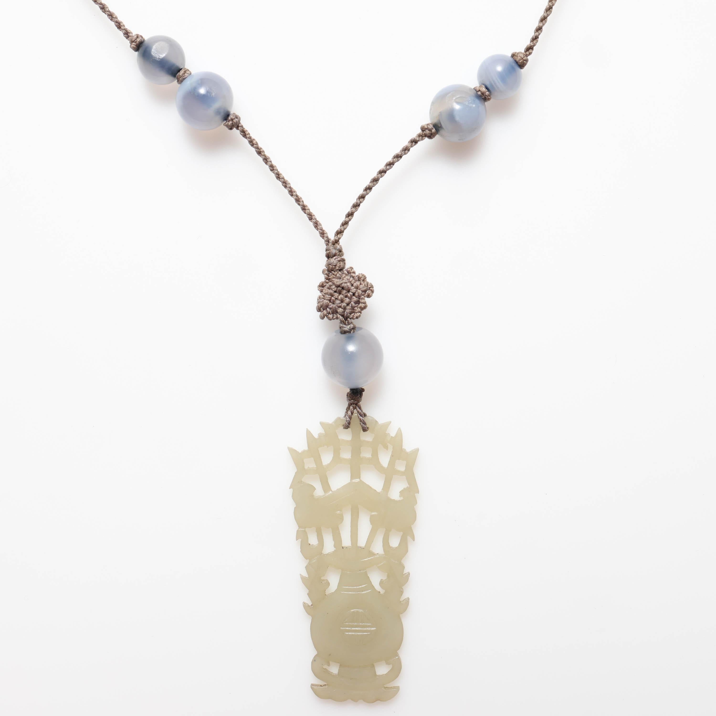 This is a rare and wholly original carved & pierced nephrite necklace from the 1920s. Still strung on its original silk and embellished with knots, rock crystal quartz, and natural blue agate. This flapper-era treasure is a creation of spectacular