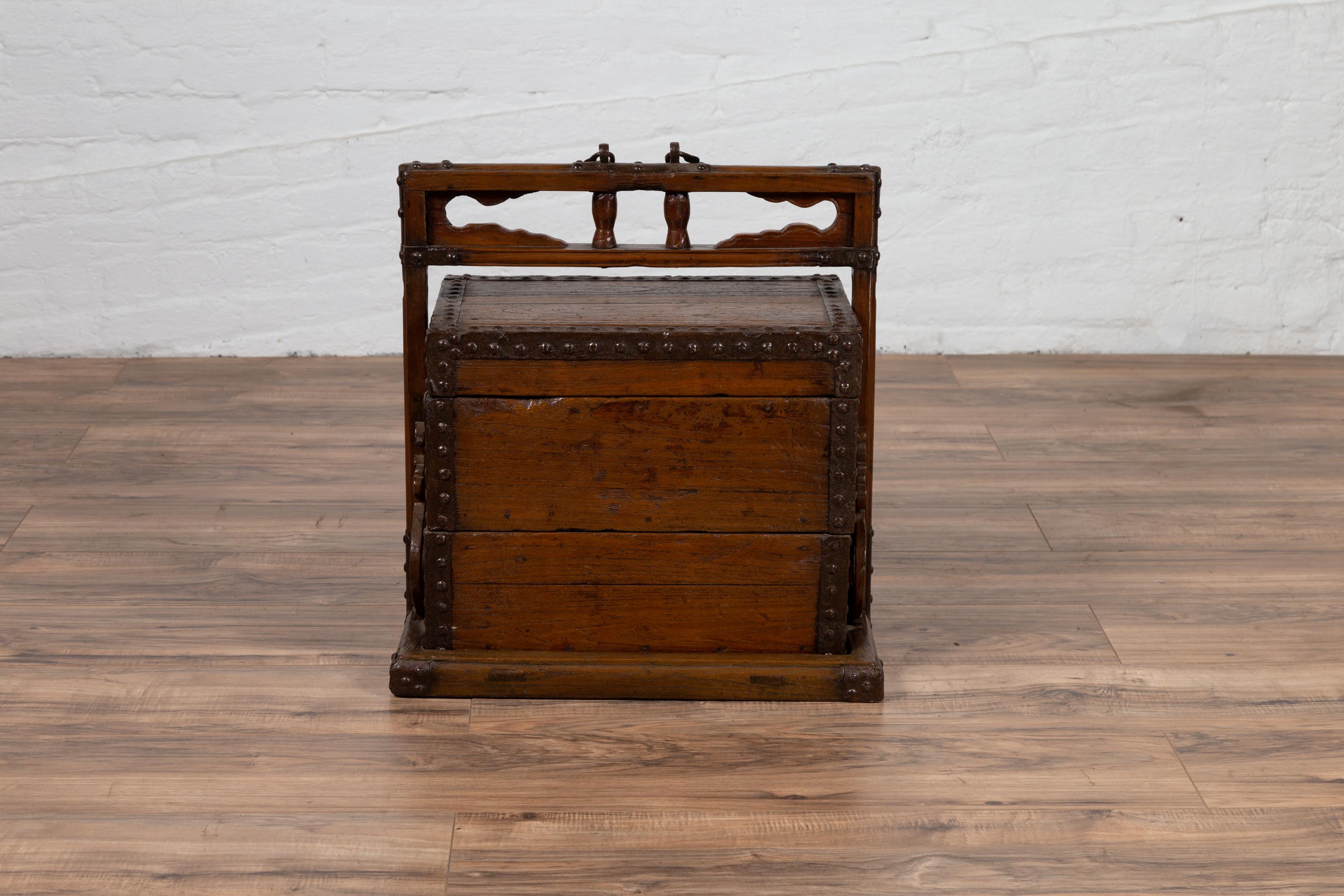 An antique Chinese wooden wedding carrying treasure box from the early 20th century, with large handle and nailheads. Born in China during the early years of the 20th century, this charming wedding box features a linear silhouette, perfect accented