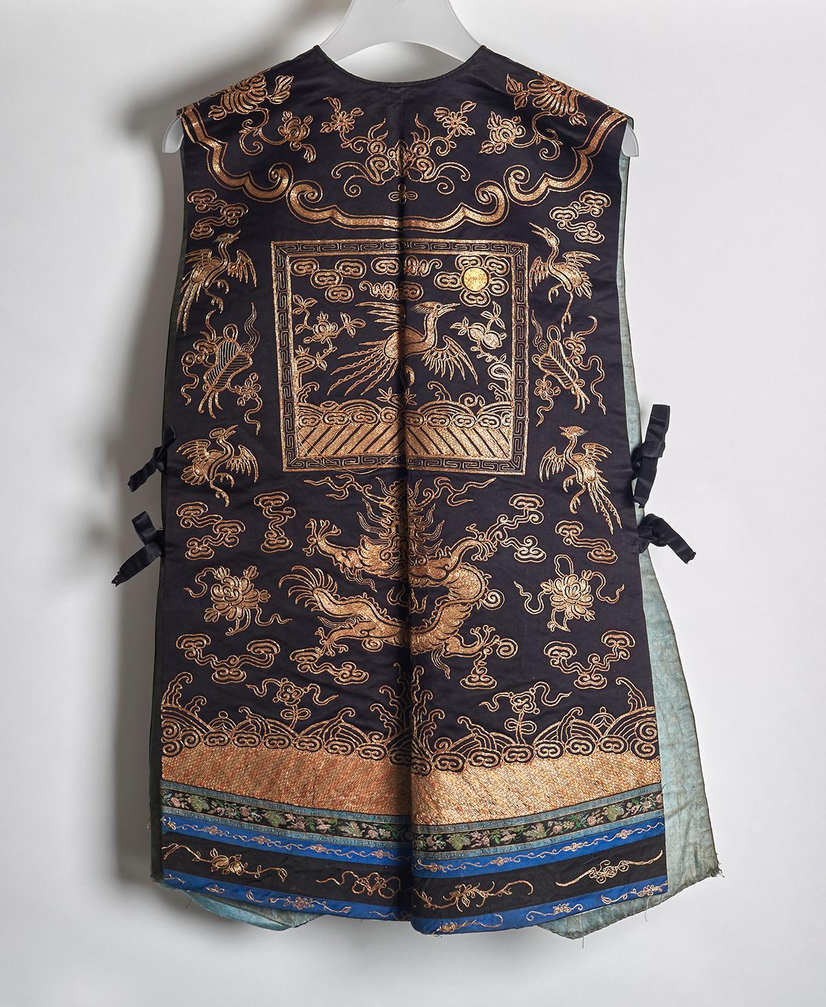 A very fine antique Chinese xiape ladies court waistcoat embroidered with silver thread with scrolling dragons amidst clouds above waves and with a pheasant 5th rank badge embroidered to the front and back. The black satin waistcoat with ties and