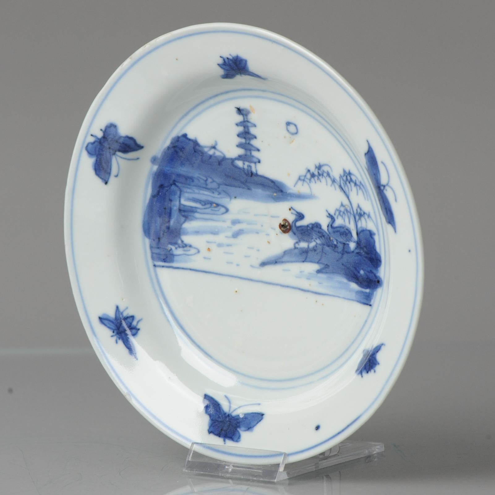 A very nicely decorated Late Ming Blue and White Porcelain Dish with a landscape scene situated in two concentric circles with Ducks/Geese under a pine tree in a mountainious landscape with a pagode in the background. The moon at te sky. The border