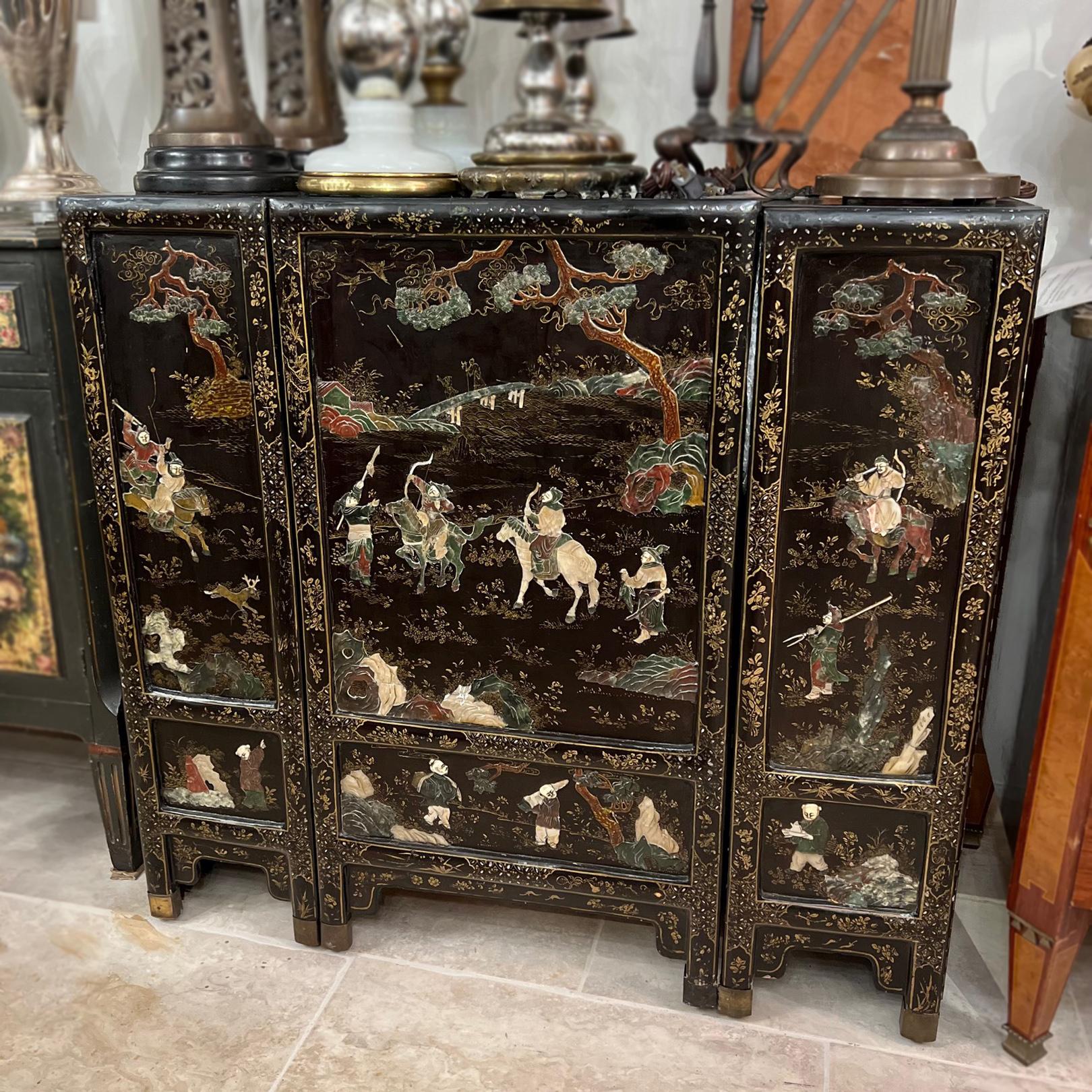 A circa 1920's black-laquered Chinese cabinet with inlayed stone and mother-of-pearl figures.

Measurements:
Height: 36