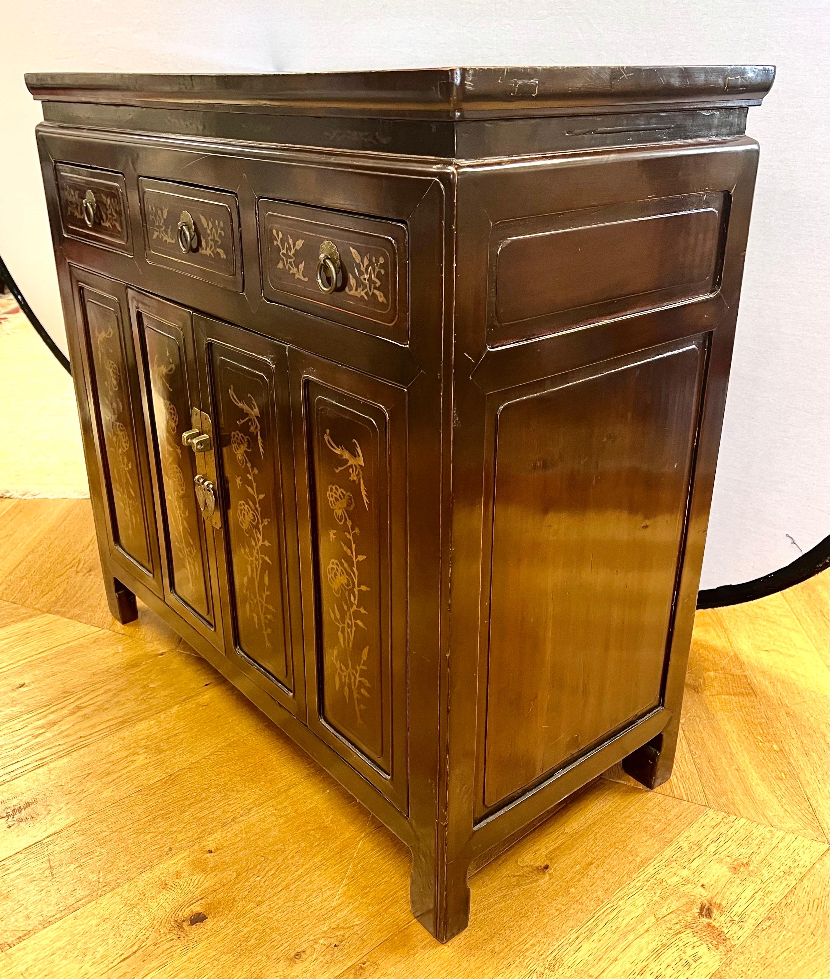 Magnifique cabinet laqué datant du milieu ou de la fin du 19e siècle. Décoré de fleurs et de feuillages en émail. Trois tiroirs sur deux portes ouvrant sur des étagères. Monté avec sa quincaillerie d'origine en laiton. Elle présente une magnifique