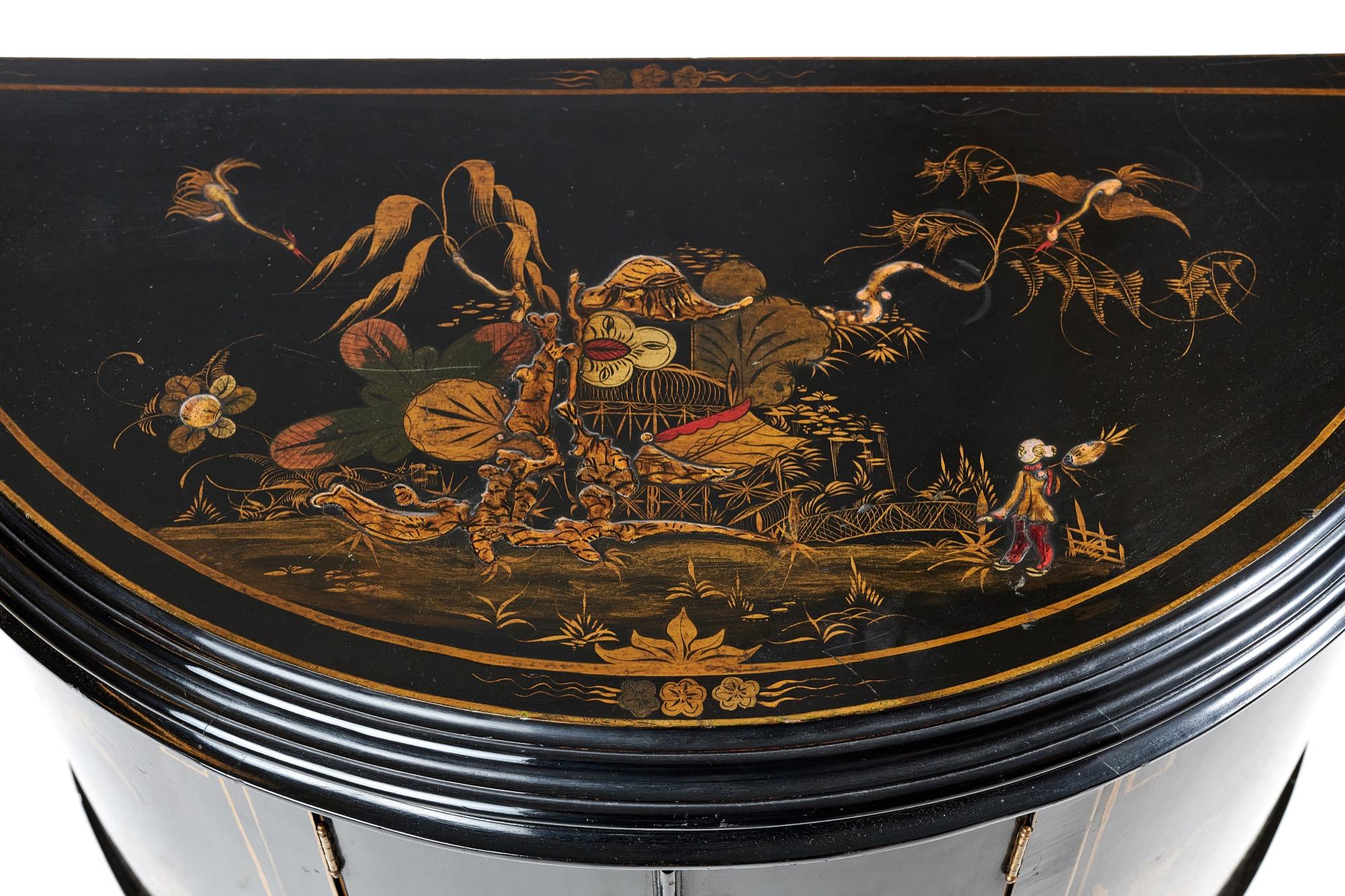 Antique Chinoiserie decorated Demi Lune shaped two door side cabinet having a black colour background, the top decorated with a figure in a garden scene, two centre doors opening to reveal a single shelf interior. The door fronts and sides are
