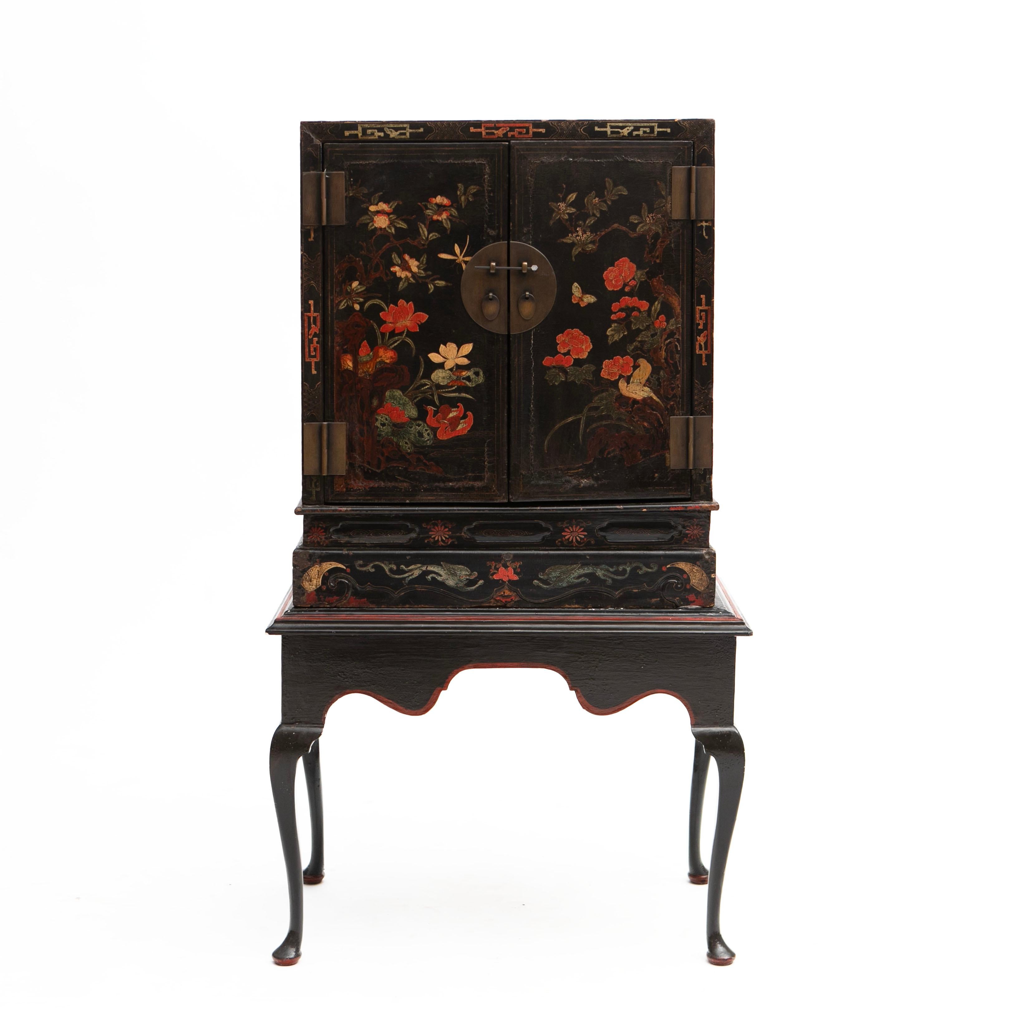 Chinese Qing dynasty cabinet with original chinoiserie decorations rasied on later stand.
Cabinet elaborately decorated with flowers painted with polychrome lacquer on a thick black lacquer base. Later red and black stand.

A beautiful and