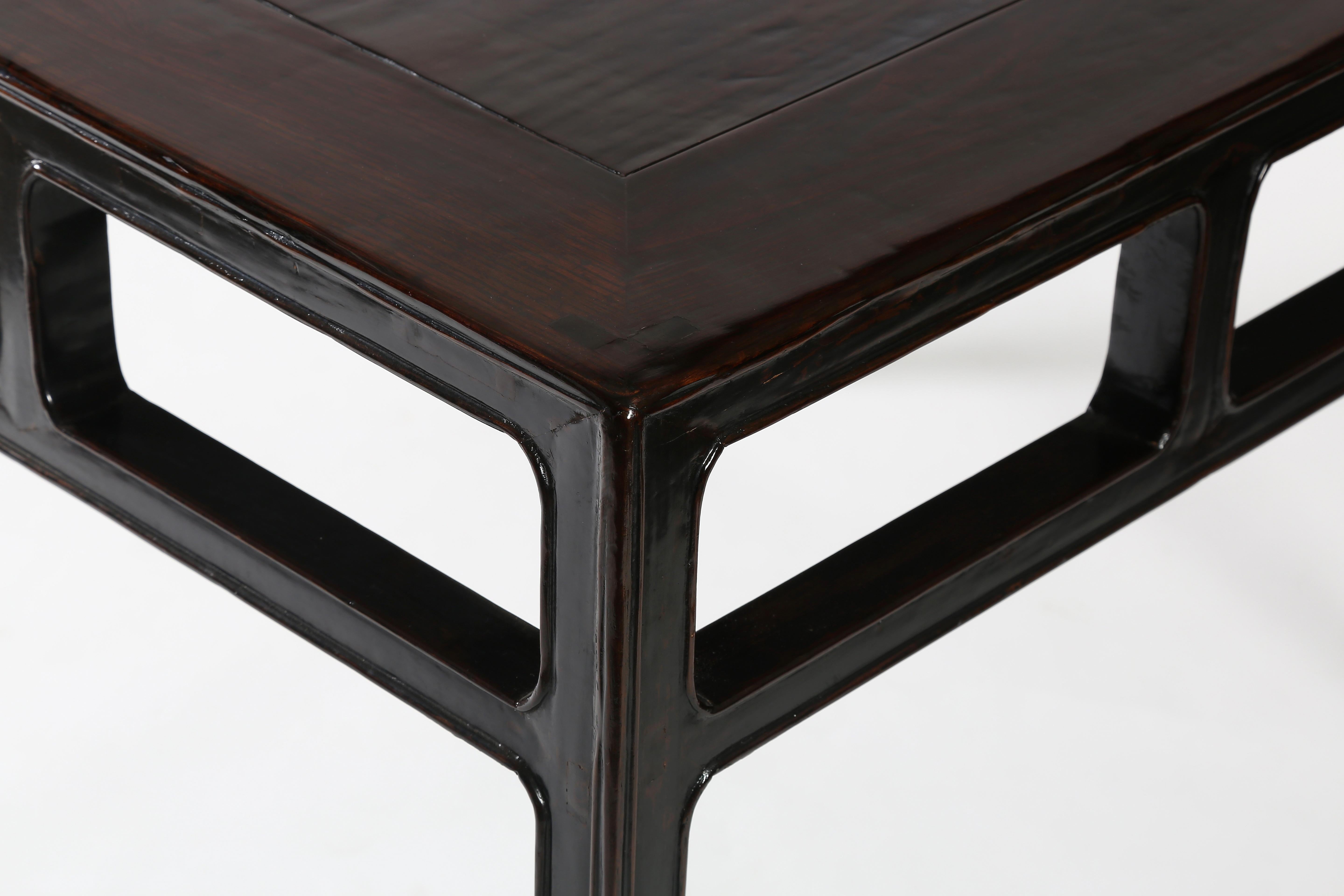 The fine square table is topped with a floating panel, enclosed within a flush sided frame, supported on square-sectioned corner legs, braced with straight stretchers and vertical struts forming rounded corner rectangular openings. The straight legs
