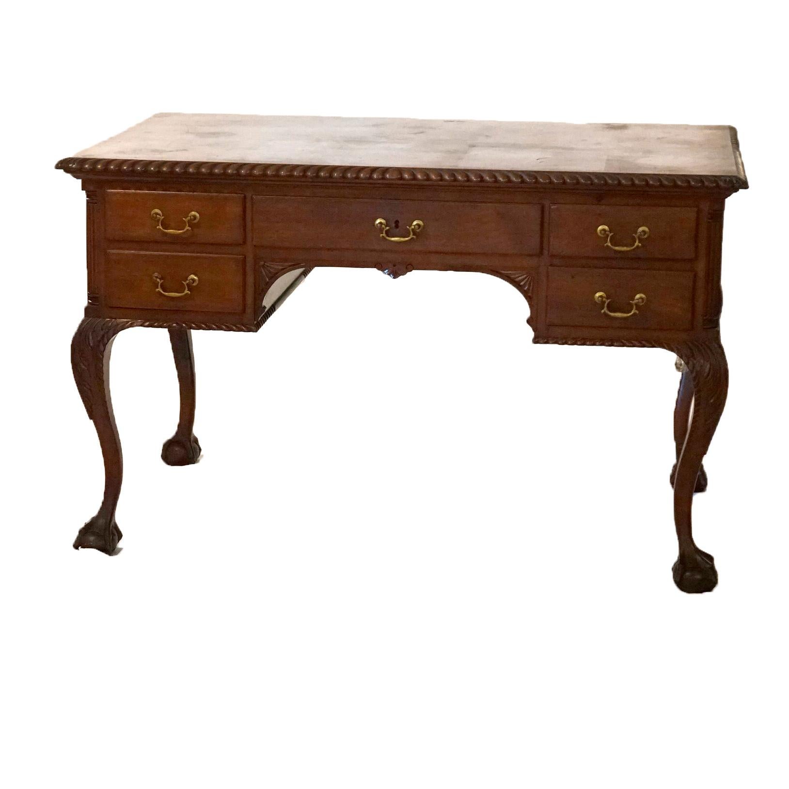 An antique Chippendale style knee hole desk offers mahogany construction with top having rope twist trim over central drawer with flanking smaller drawers and reeded columns, raised on cabriole legs having carved acanthus knees and claw and ball