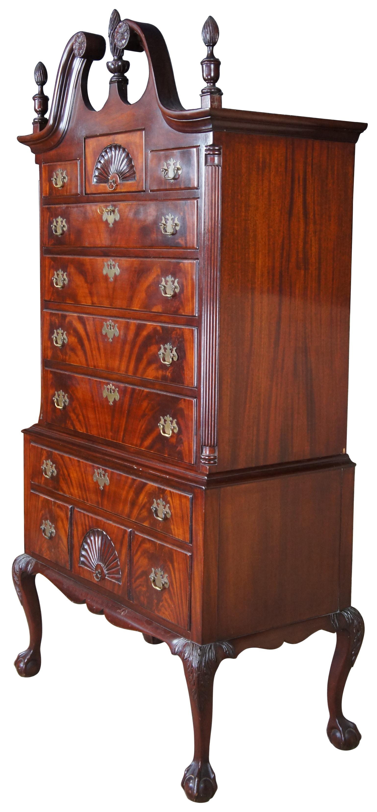 20th century Chippendale highboy dresser or chest. Made of flamed mahogany featuring a open pediment with torchiere finials, ten drawers and ball and claw feet. Measure: 81