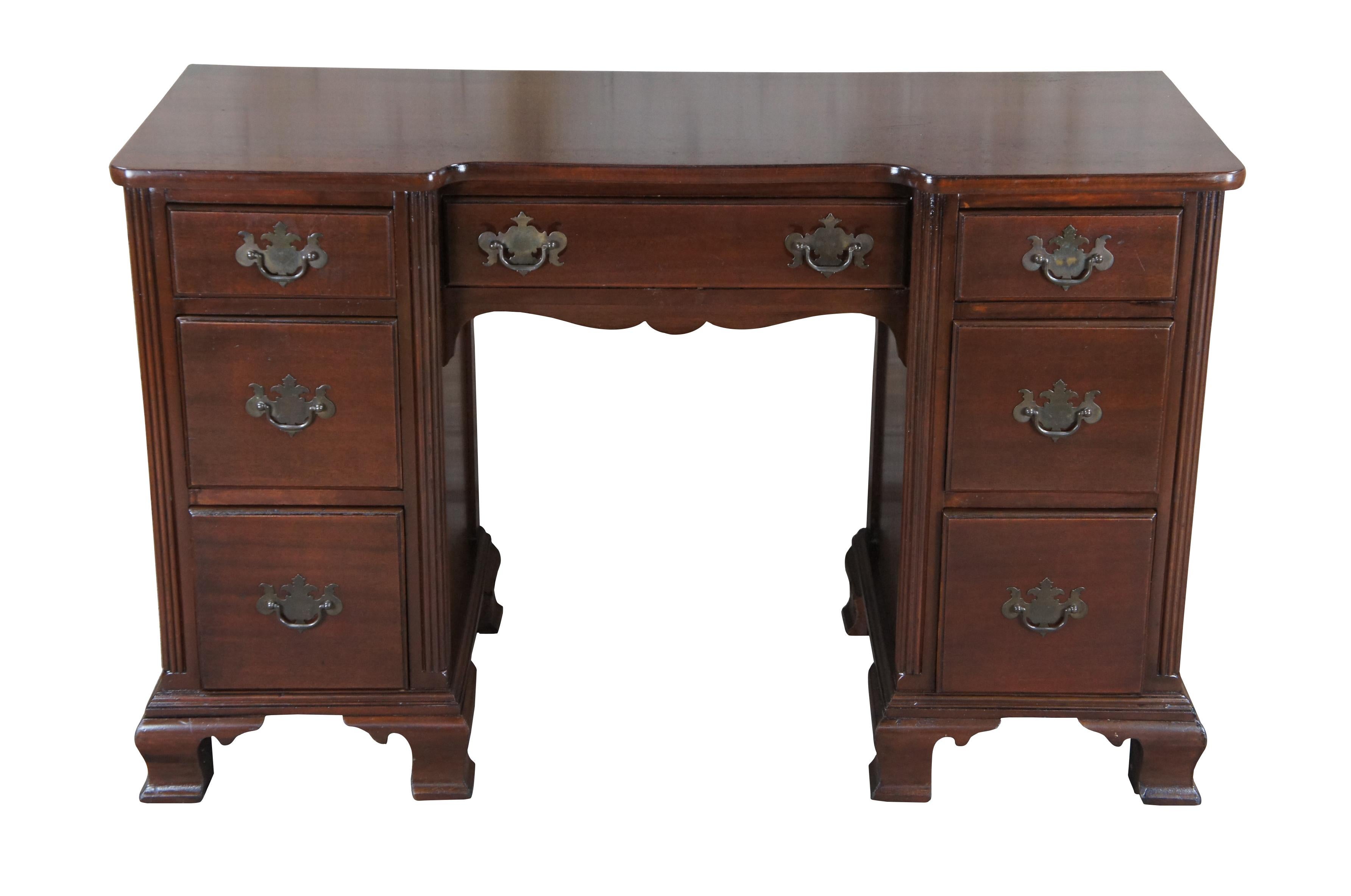 Circa 1940s mahogany knee hole writing or vanity desk featuring seven drawers with colonial brass bat wing hardware and matching serpentine mirror with open pediment and pineapple finial.

Measures: 48