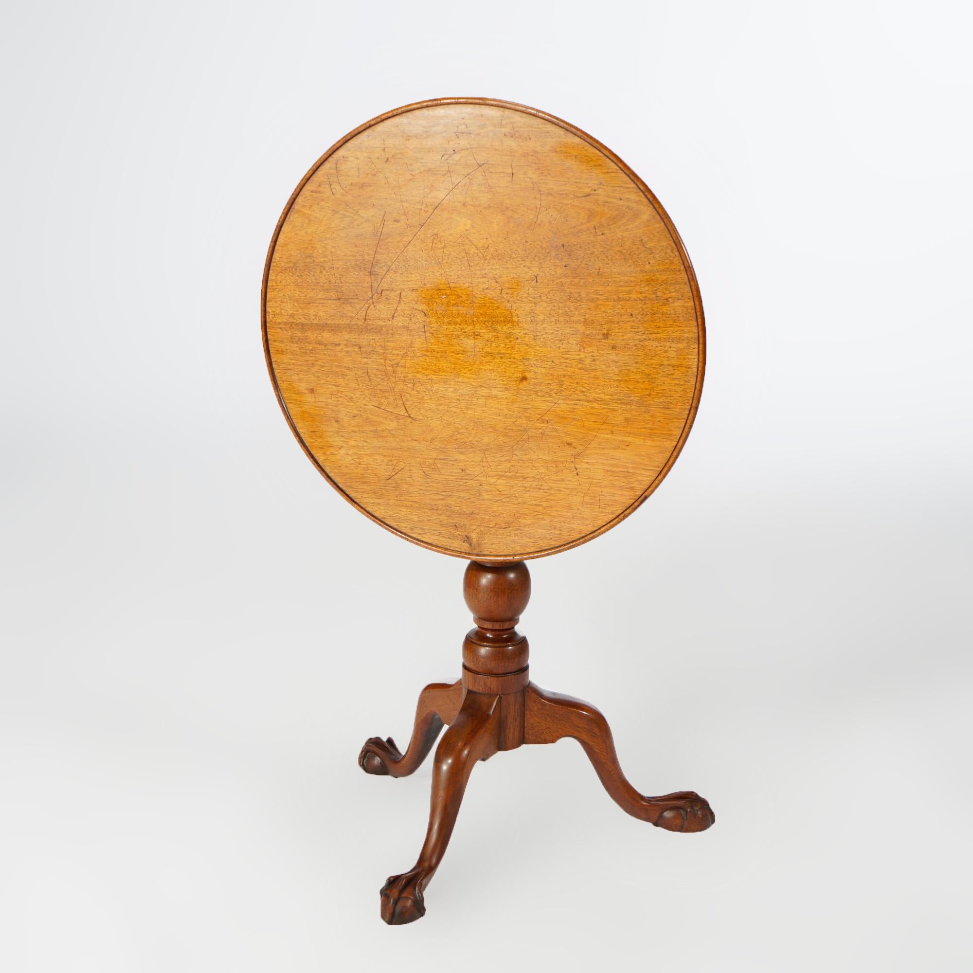 An antique Chippendale tilt top tea table offers mahogany construction with round top having slight lip over turned column and raised on three cabriole legs terminating in carved claw and ball feet, 18th or early 19th century

Measures - 26.75''H