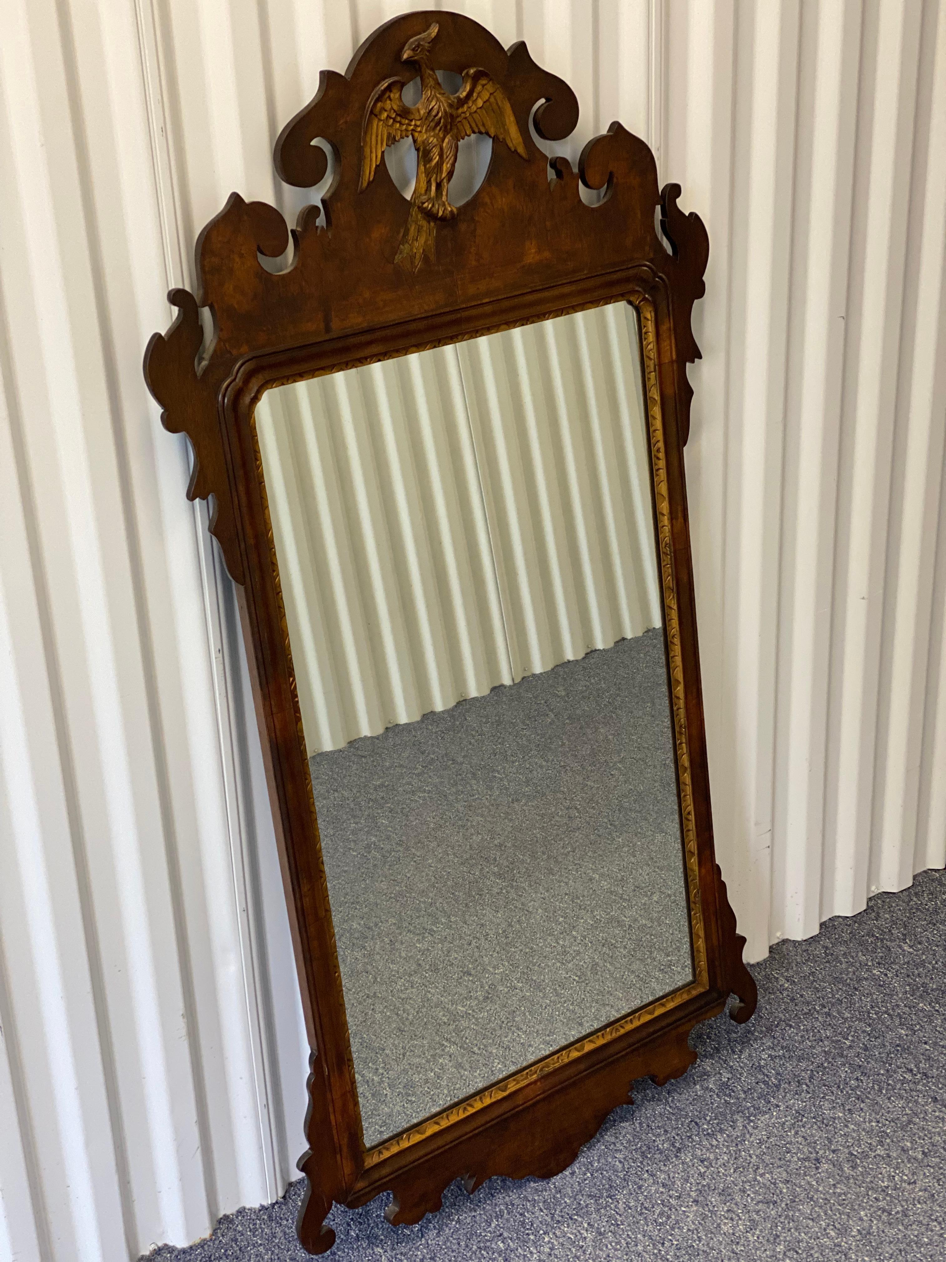 Antique Chippendale Style sculpté Mahogany Mirror avec Phoenix Crest
Le miroir rectangulaire avec une découpe ronde en haut avec un phénix aux ailes déployées doré, possédant un cadre complexe avec une crête à volutes et une frise inférieure avec