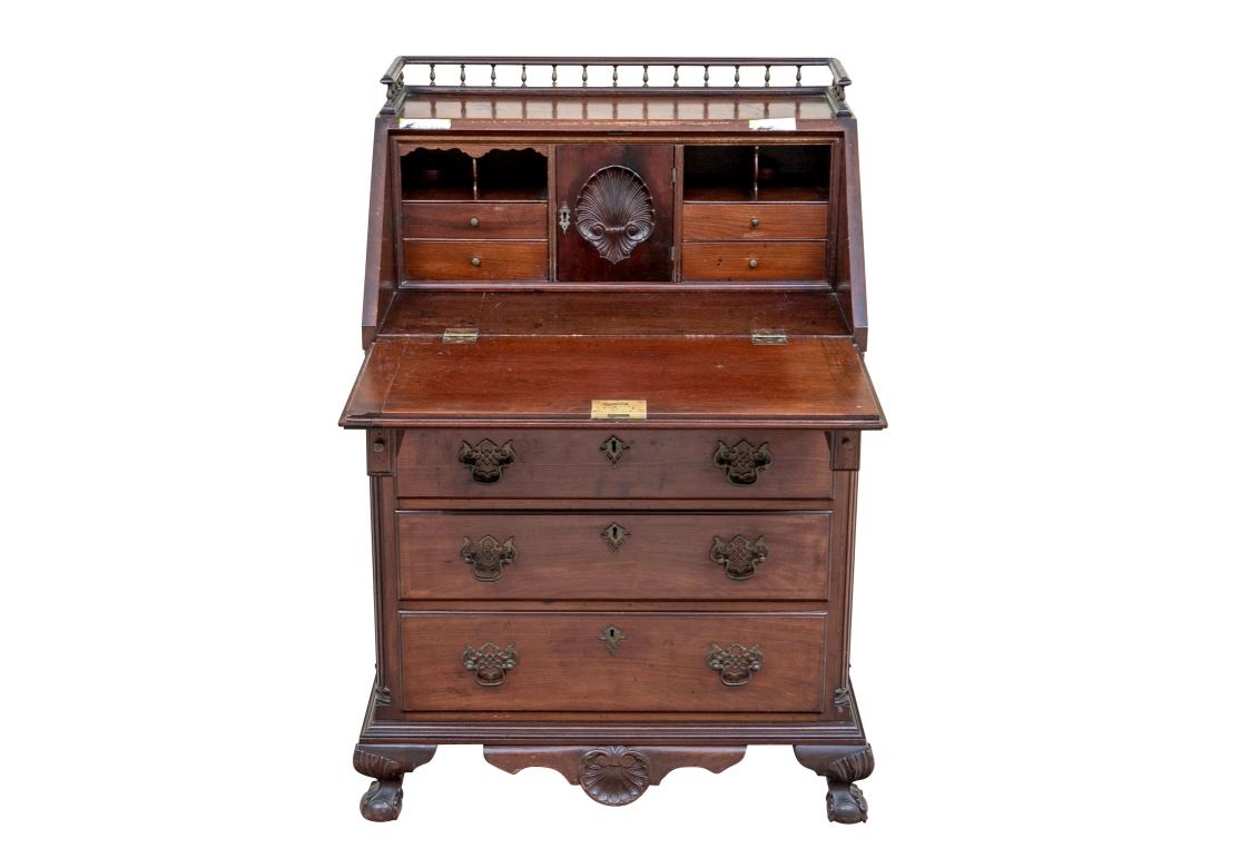 A well made and very decorative Drop Front Desk with boldly carved Scallop Shells, intricate brass Bat Wing pulls and escutcheons, four dove tail construction drawers, Gallery top and Ball and Claw foot. The writing surface door drops to reveal four