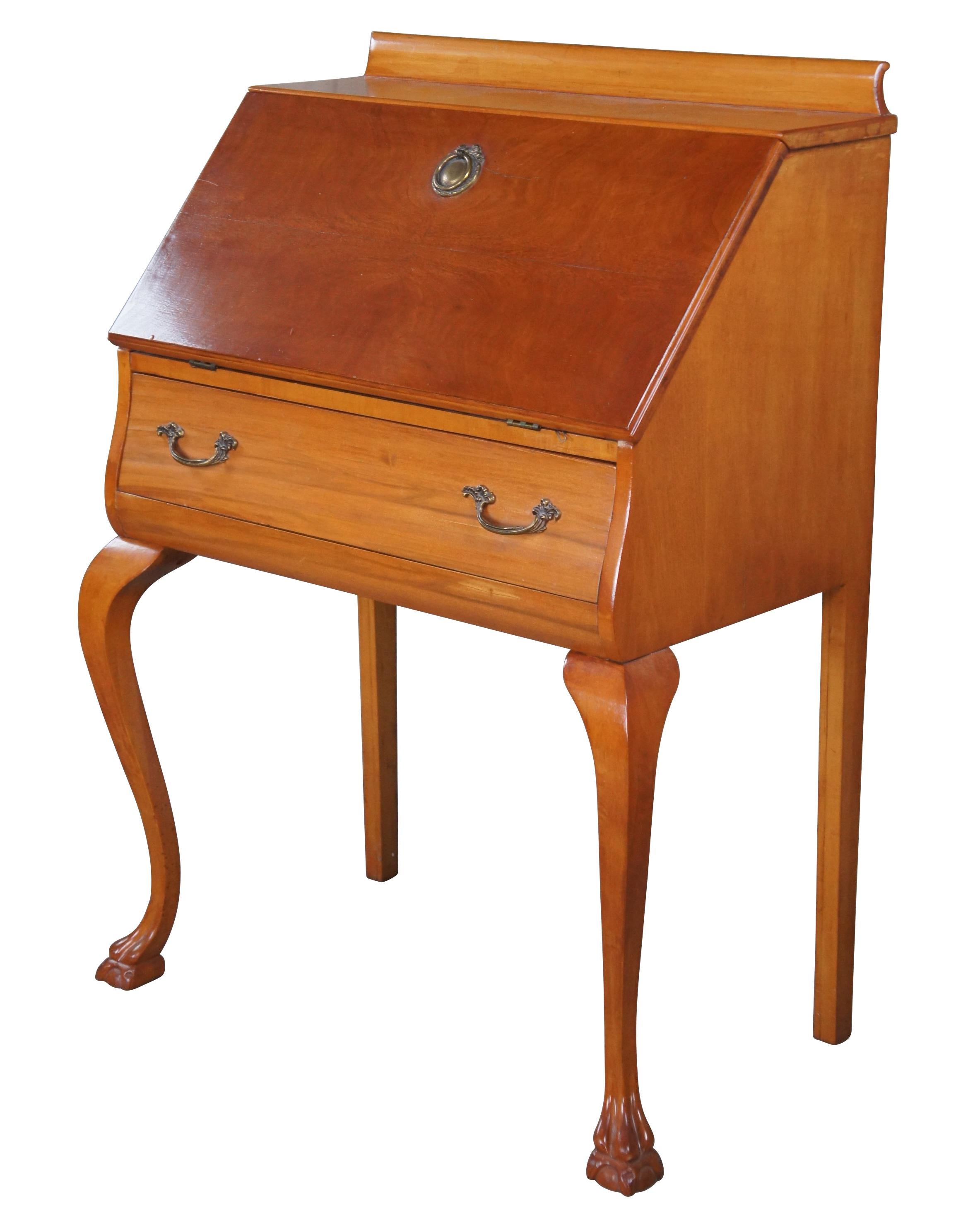 An antique early 20th century ladies' secretary desk. Made from walnut with a maple writing surface. Features a drop front with neoclassical brass hardware over large central drawer with French pulls. Opens to seven pigeonholes and an accessory