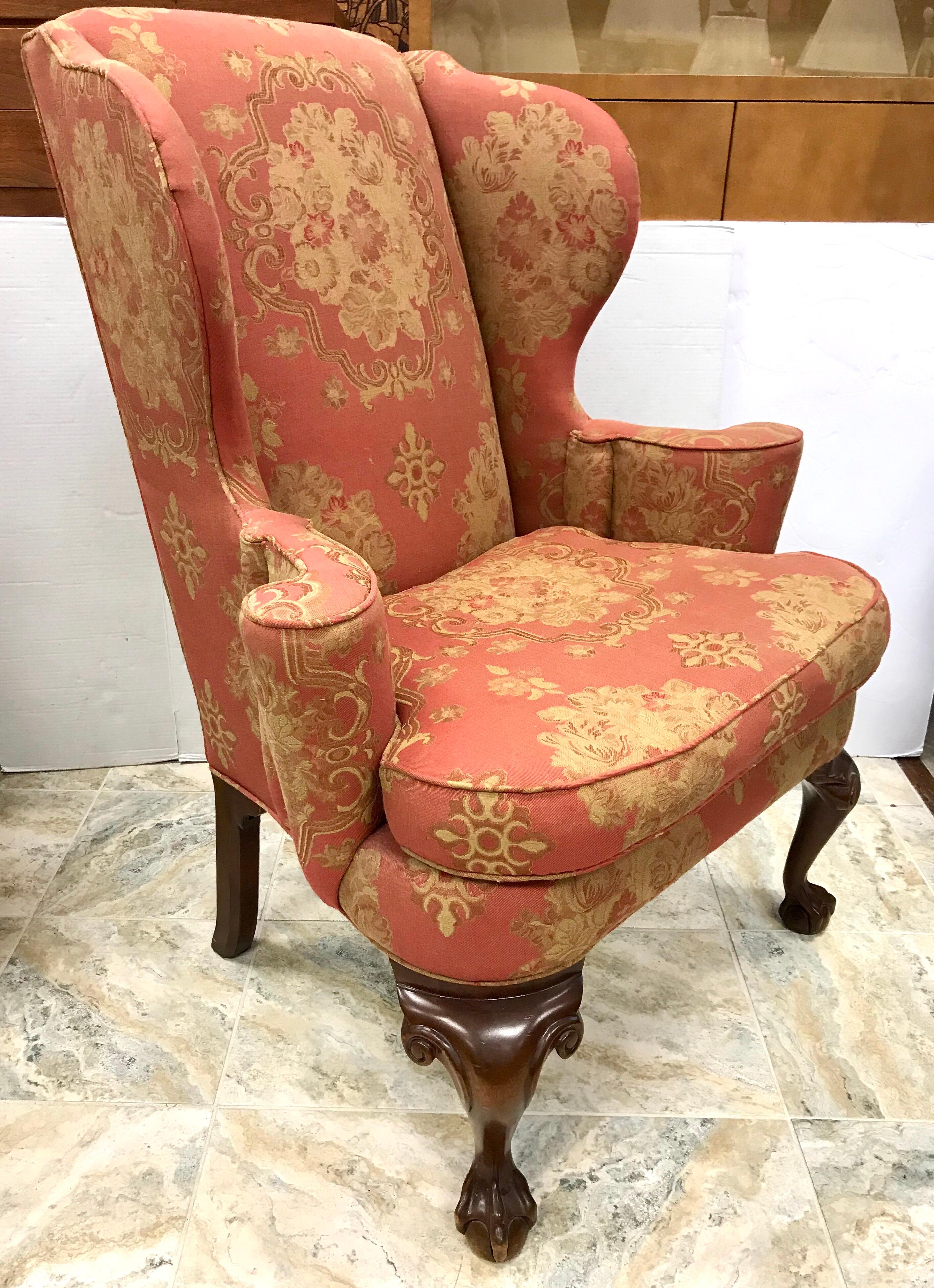 Elegant Chippendale antique wingback chair done in a gorgeous salmon and gold upholstered pattern.