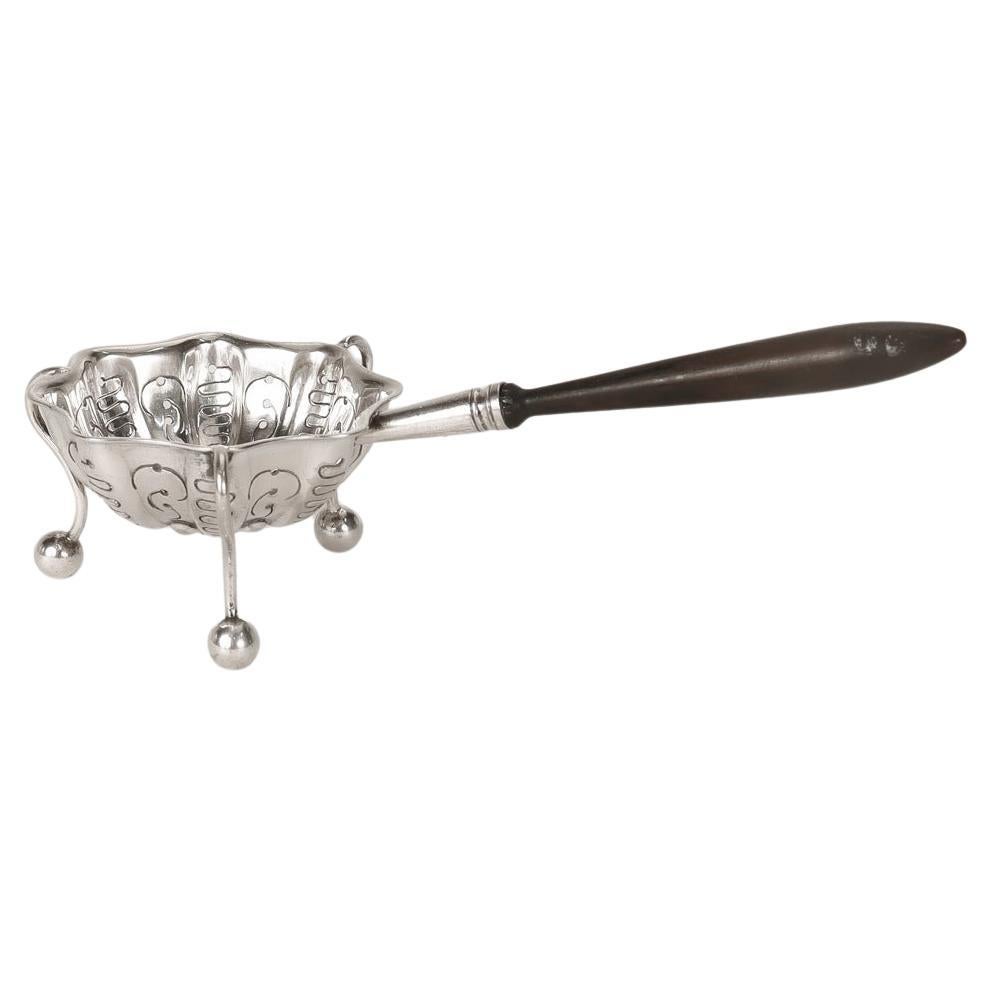 A fine French silver plated tea strainer. 

By Christofle et Cie.

With a pierced and scalloped body, curved legs, ball feet and a turned wooden handle.

Simply a wonderful, high-level tea strainer from one of France's most important