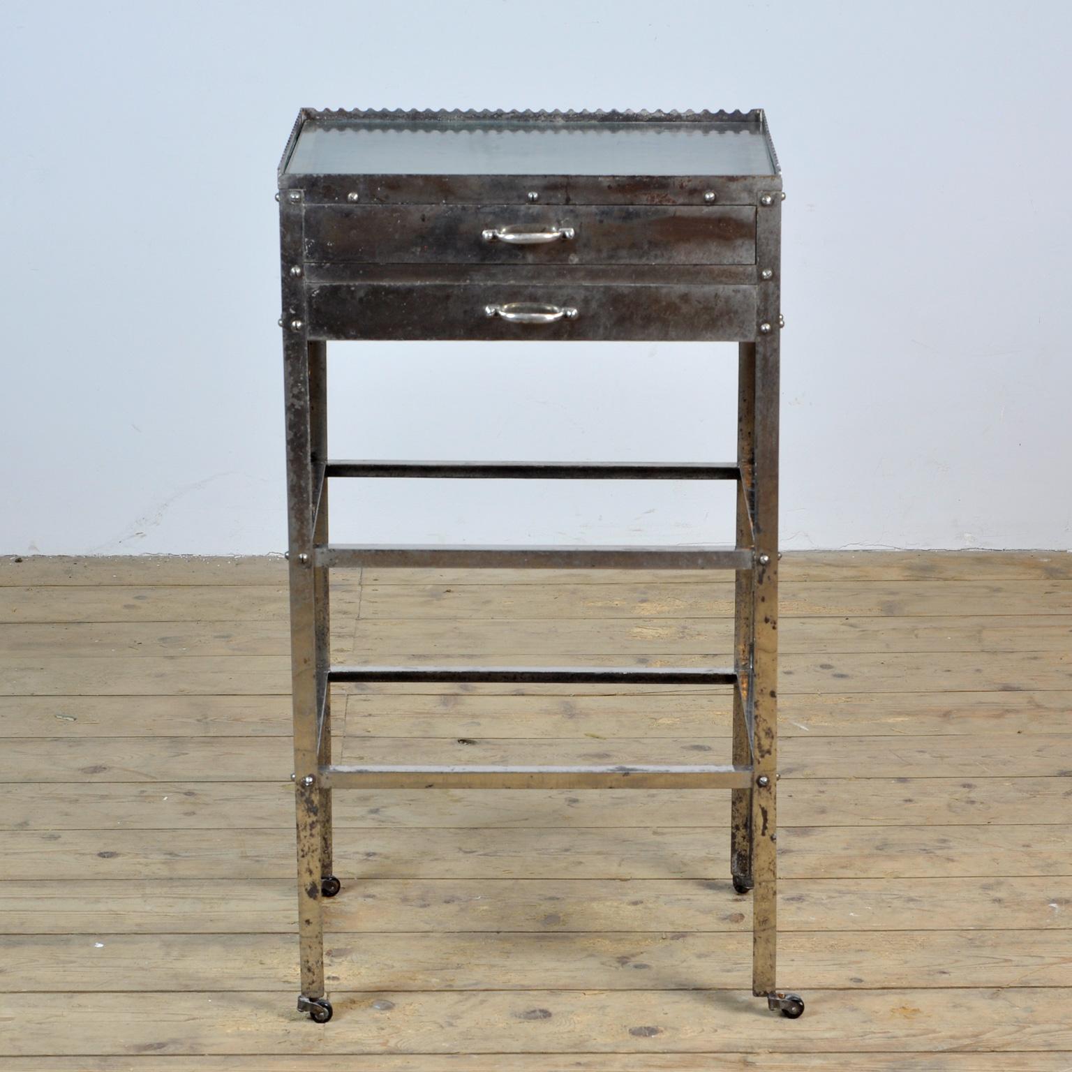Hospital trolley from circa 1920. The trolley is made of chrome-plated iron with a glass top and glass in the two drawers. The wrinkled glass is from the same period.