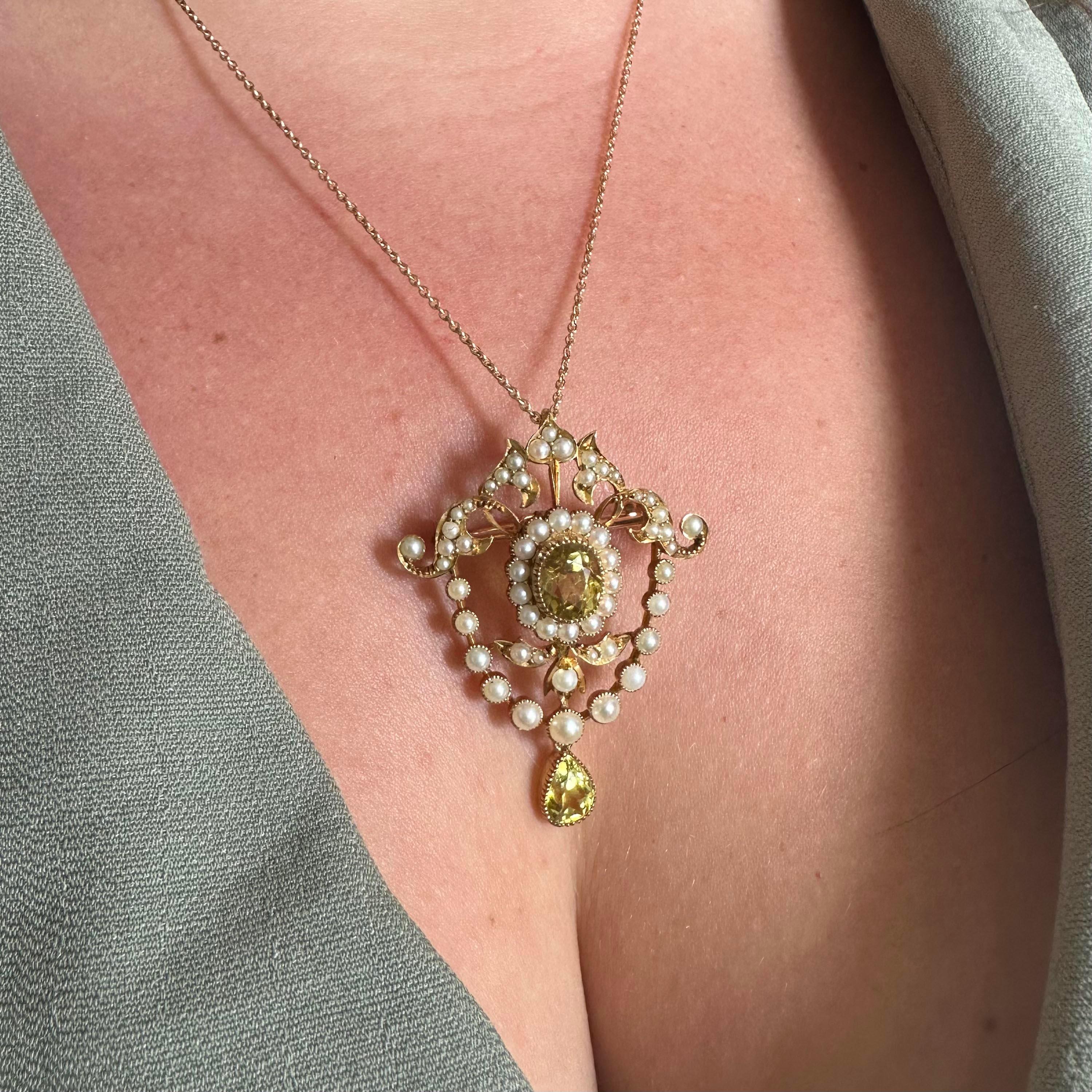 An Edwardian heliodor and pearl brooch-cum-pendant, with an oval faceted heliodor in a surrounding cluster of natural half pearls, on an openwork scroll brooch pendant, set with natural half pearls and single heliodor pear shaped pendant drop, in a