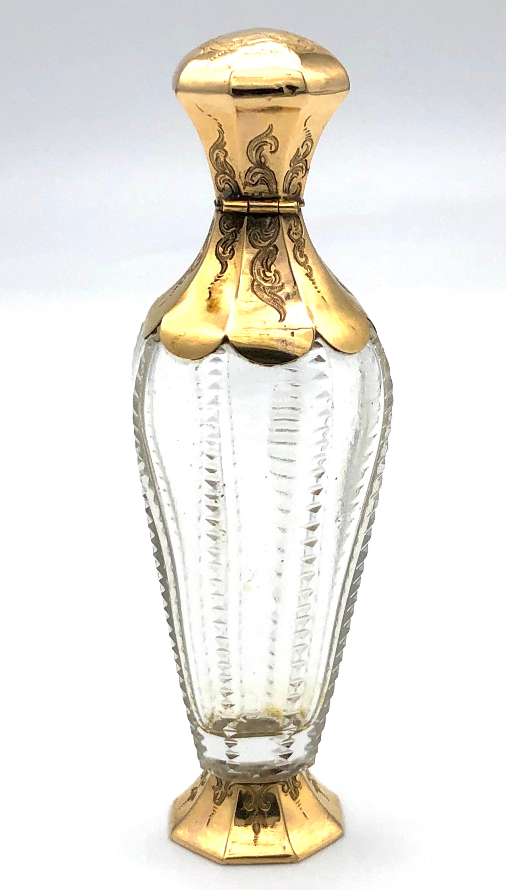 The highly elegant and slender perfume bottle is made out of gold and crystal glas.
The crystal glas is decorated with exquisitely cut triangles that form vertical lines which divide the bottle into eight segments. The scent bottle stands on a