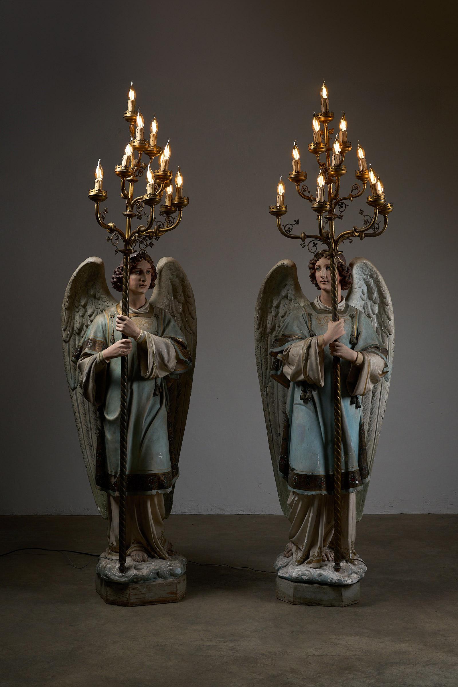 These stunning antique church candle holders, dating back to the 19th century, are captivating examples of religious artistry and craftsmanship. Each piece features a finely detailed plaster angel figure, supported by a wooden base, and holding an