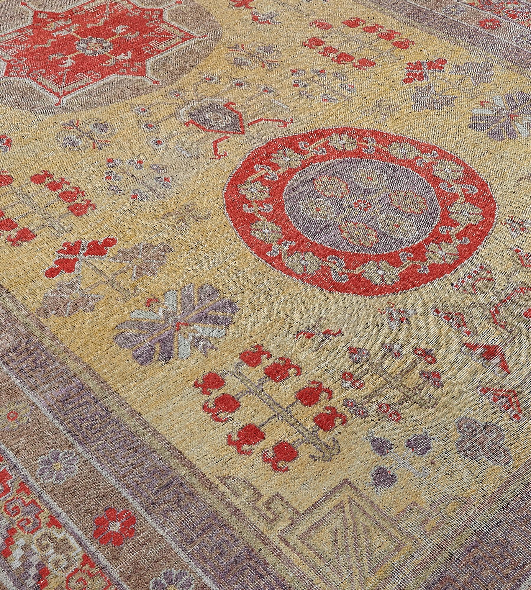 This antique, circa 1880, Khotan rug has a golden-yellow field with a variety of scattered stylized flowers and floral motifs around a column of three roundels linked by an angular hooked plant motif, the central mole-brown roundel containing a