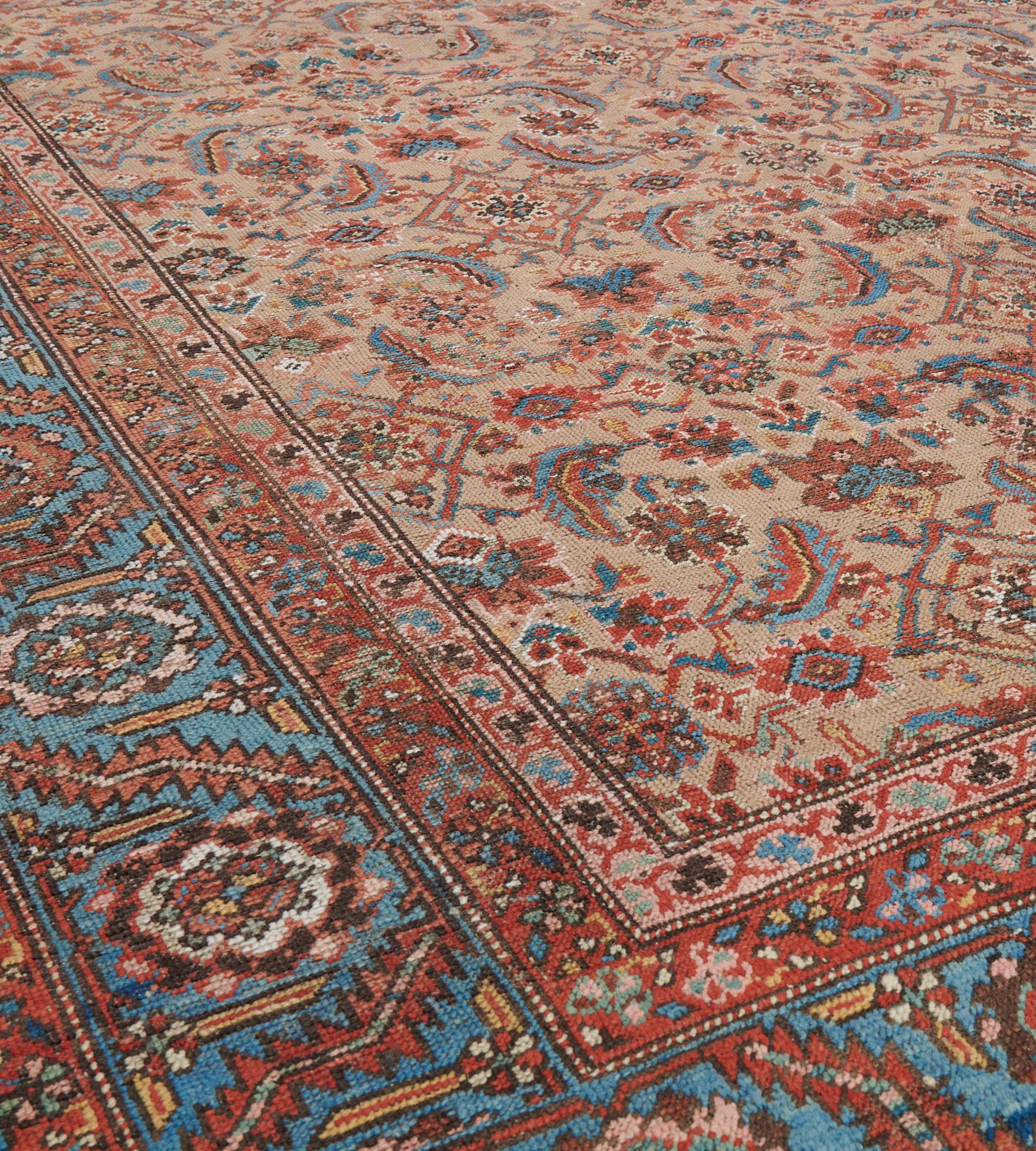 This antique, circa 1880, Bakhshaish rug has a camel-brown field with an overall herati-pattern of light blue, chocolate-brown and brick-red, in a shaded light blue border of serrated leave vine linking polychrome flowerheads and angular floral