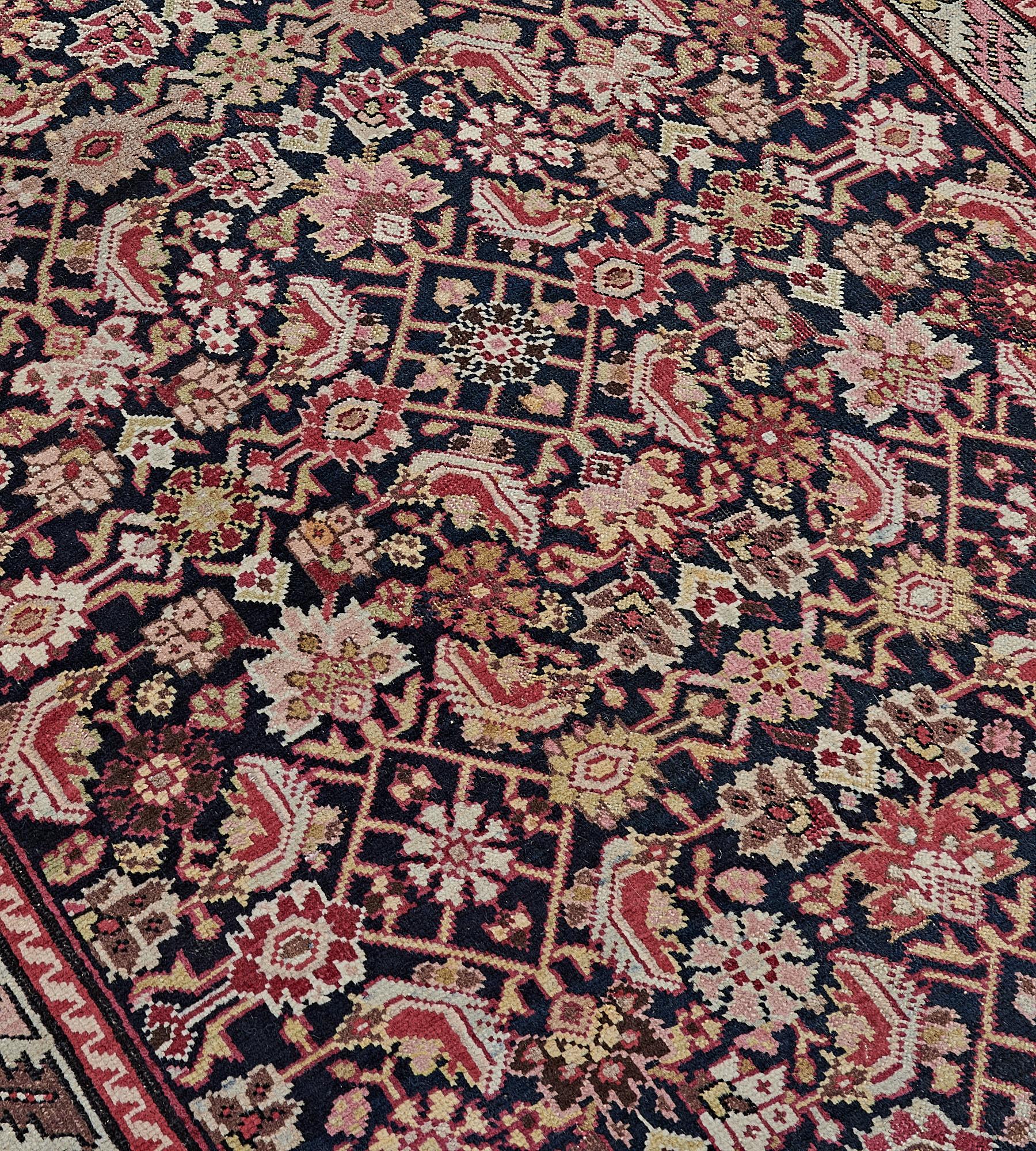 This antique, circa 1890, Karabagh runner has a charcoal-blue field with an overall herati-pattern design of dusty-pink, rust-red and golden-yellow flowerheads and serrated leaves, in an ivory narrow border of serrated leaves linking flowerheads