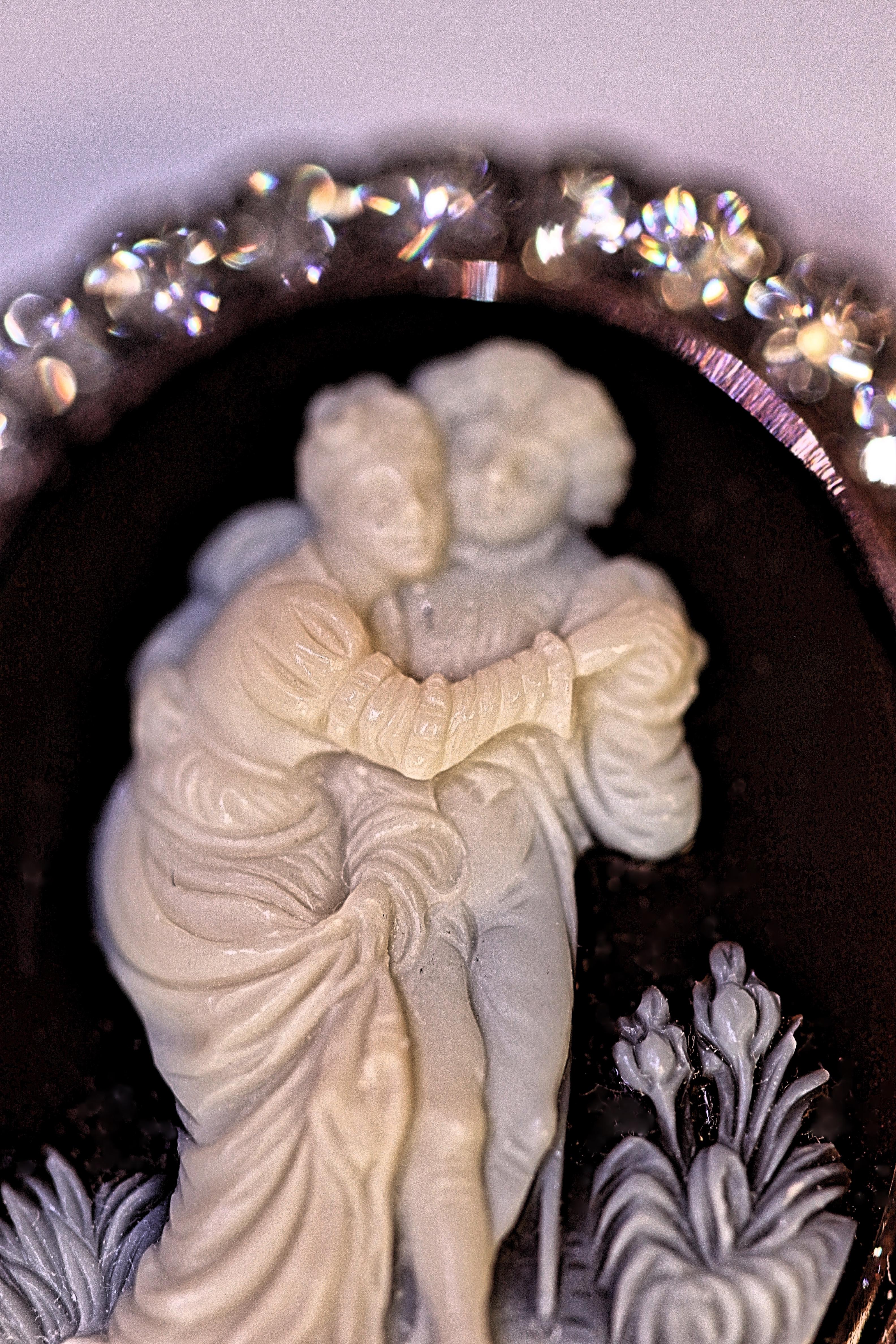 An exquisite agate cameo dating back to circa eighteenth century.  The brown and cream colored cameo is a finely crafted picture of a male and female embracing.  The cameo is surrounded by 32 lively old mine cut diamonds with an approximate weight