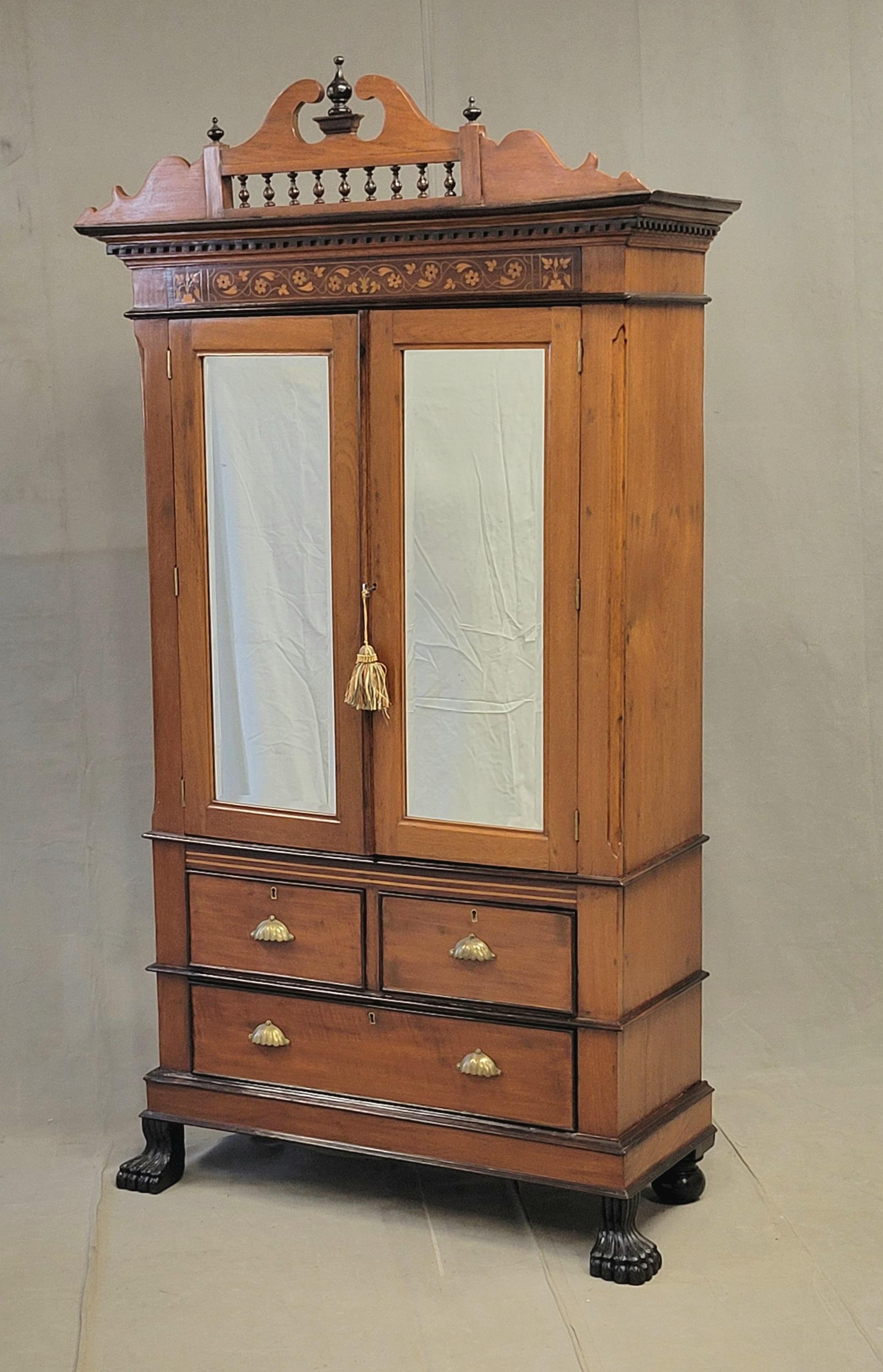Un bellissimo e funzionale mobile anglo-indiano antico del 1900 con fregio floreale in legno satinato intarsiato. Il corpo del mobile è realizzato in teak, mentre le finiture scure sono in palissandro ebanizzato. La corona intagliata e decorata