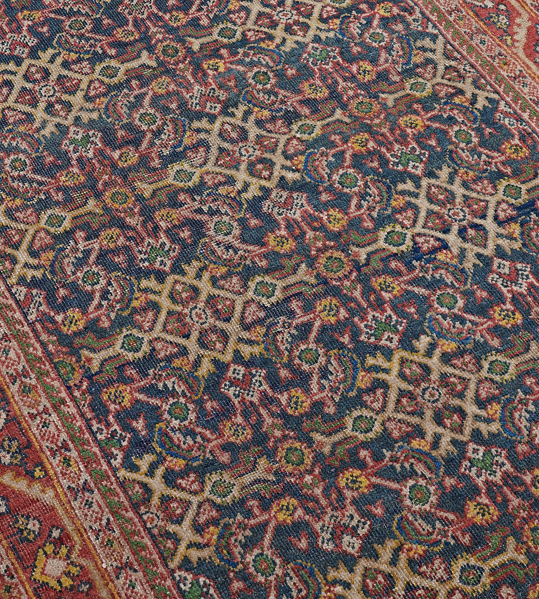 This antique, circa 1900, Sultanabad runner has a shaded sea-blue field with an overall polychrome herati-pattern, in a brick-red border of meandering serrated vine issuing floral sprays between ivory linked flowerhead and part-lozenge stripes, an