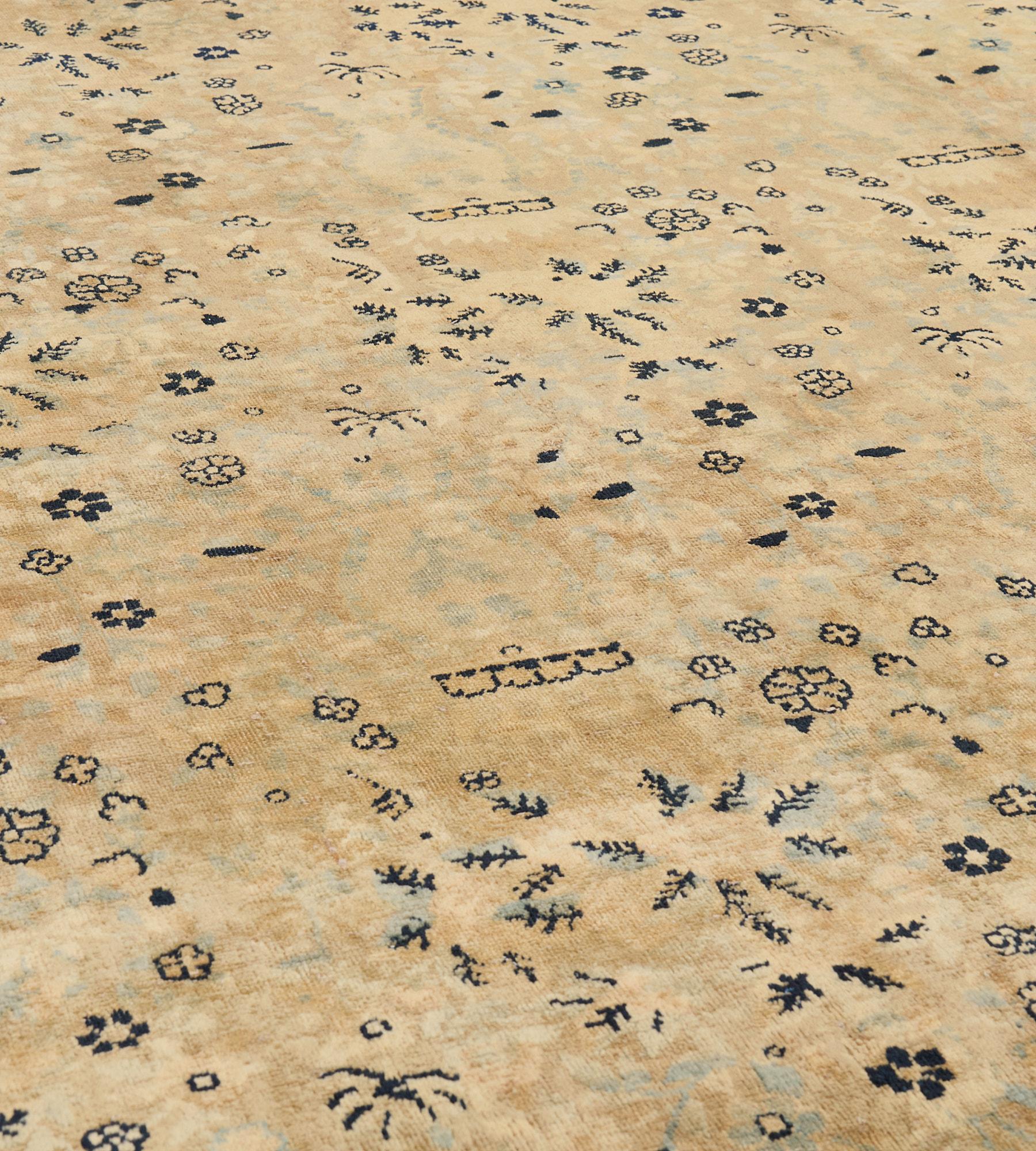 Dieser antike, um 1920 entstandene persische Kirman-Teppich zeigt ein sandgelbes Feld mit einem Gesamtmuster aus horizontalen Reihen elfenbeinfarbener Vasen, aus denen jeweils dichte hellblaue, elfenbeinfarbene und indigoblaue Blumensprenkel