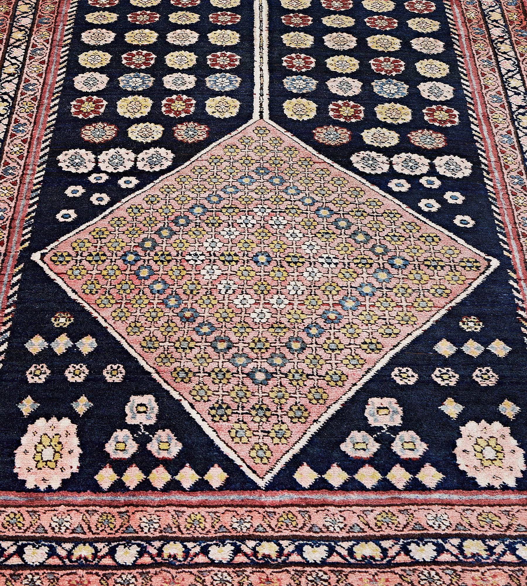 This antique, circa 1900, Bidjar Runner has an indigo-blue field with a central column of three large shaded pink linked lozenges each containing a dense flowerhead panel surrounded by scattered polychrome flowerheads and a pair of rabbits at each