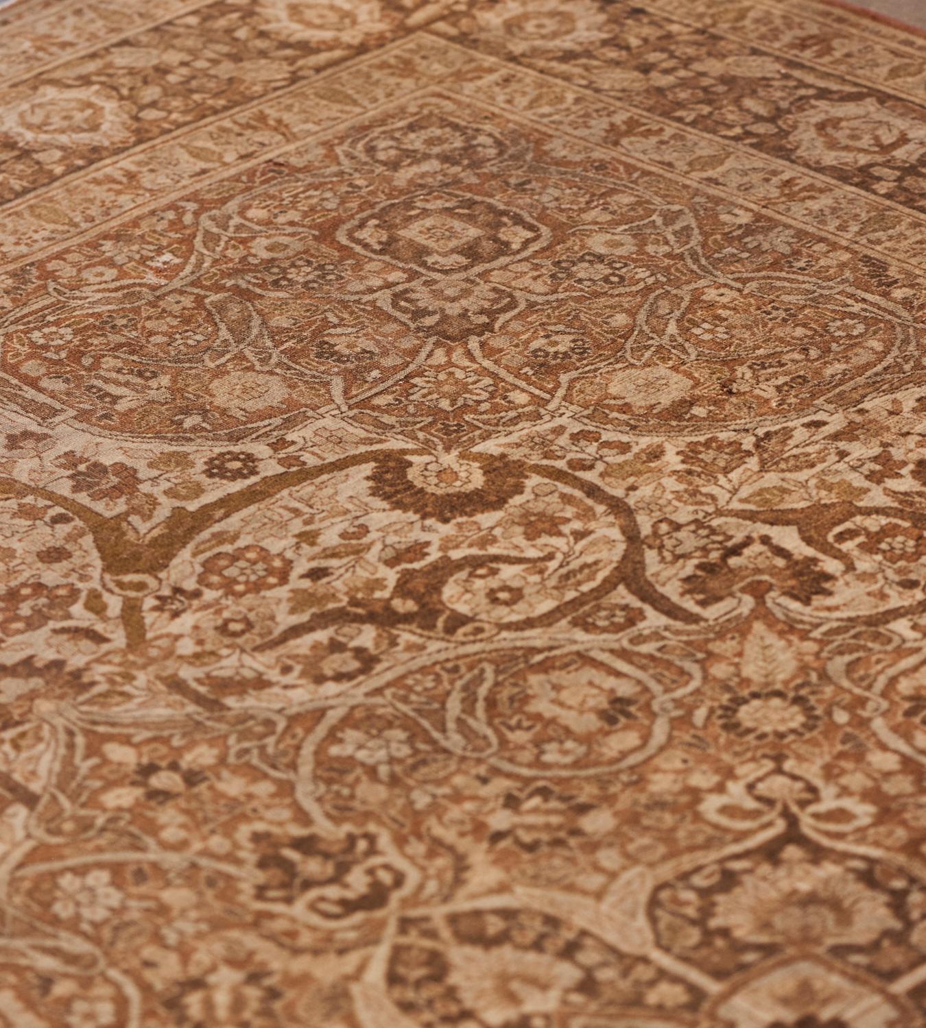 This antique, circa 1900, Tabriz rug has a pale-brown field with a dense floral and arabesque vine around a central light brown and ivory cusped medallion with pendants the medallion with a central ivory lozenge issuing soft-brown soft brown