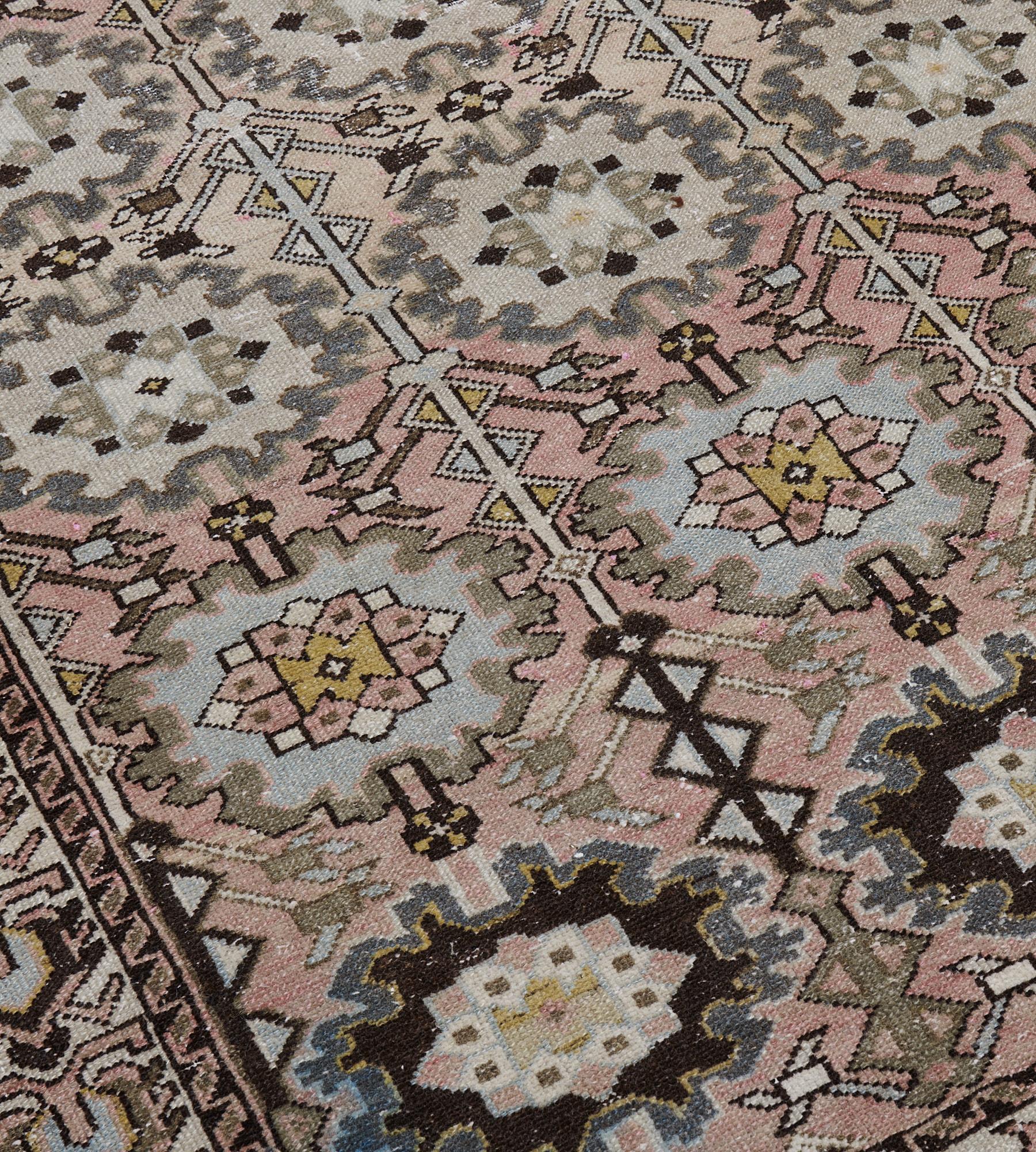 This antique, circa-1900, Malayer rug has a dusty-pink field with three columns of linked charcoal-brown, ivory and ice-blue bold palmettes with a pair of angular vine columns issuing angular floral motifs, in an ivory border of linked hooked