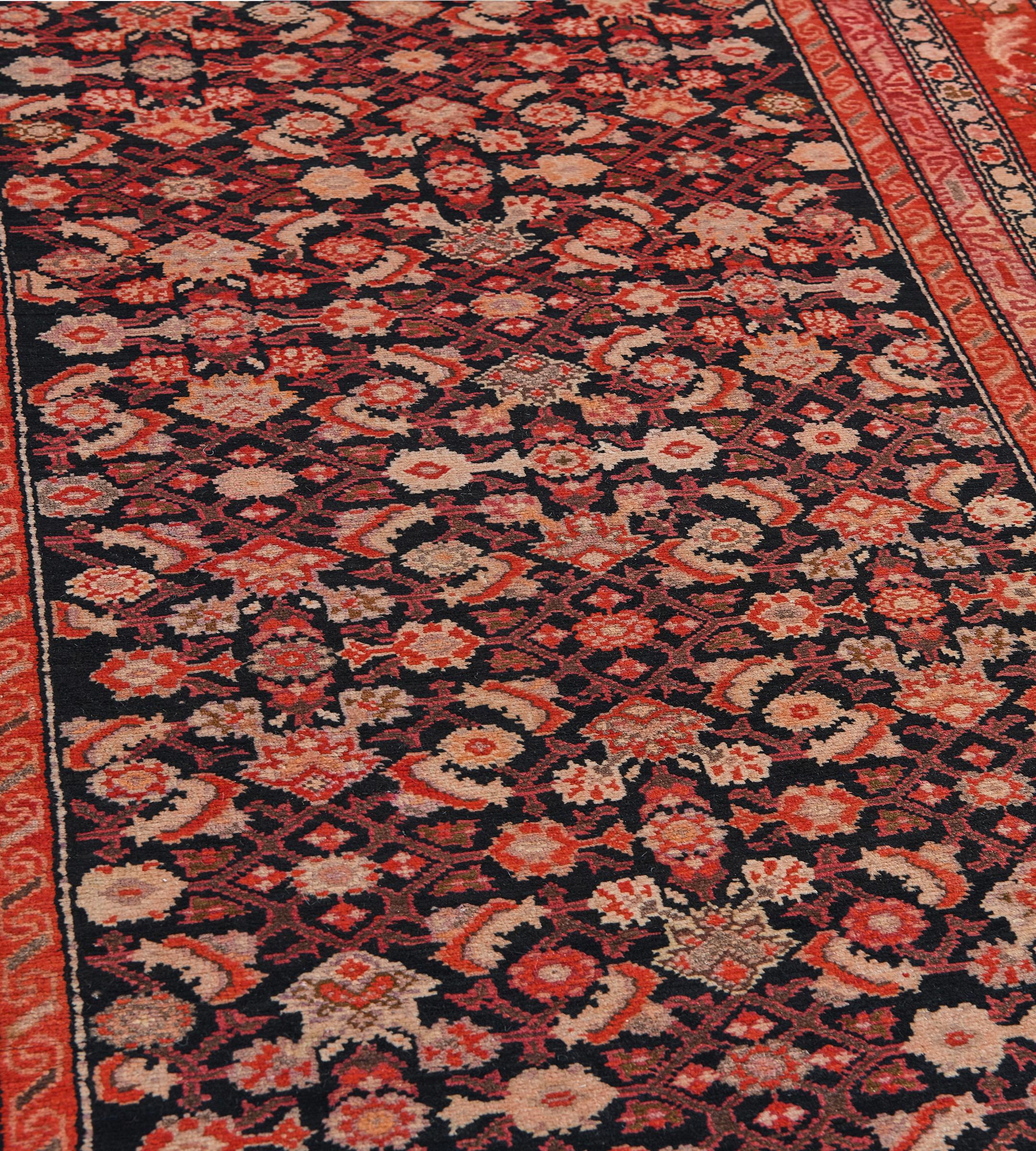 Cette ancienne coulisse du CIRCA, datant de 1900, présente un champ noir anthracite avec un motif herati rouge tomate, brun chamois et brun taupe, dans une étroite bordure rouge tomate de feuilles d'acanthe enroulées et de vignes florales, des