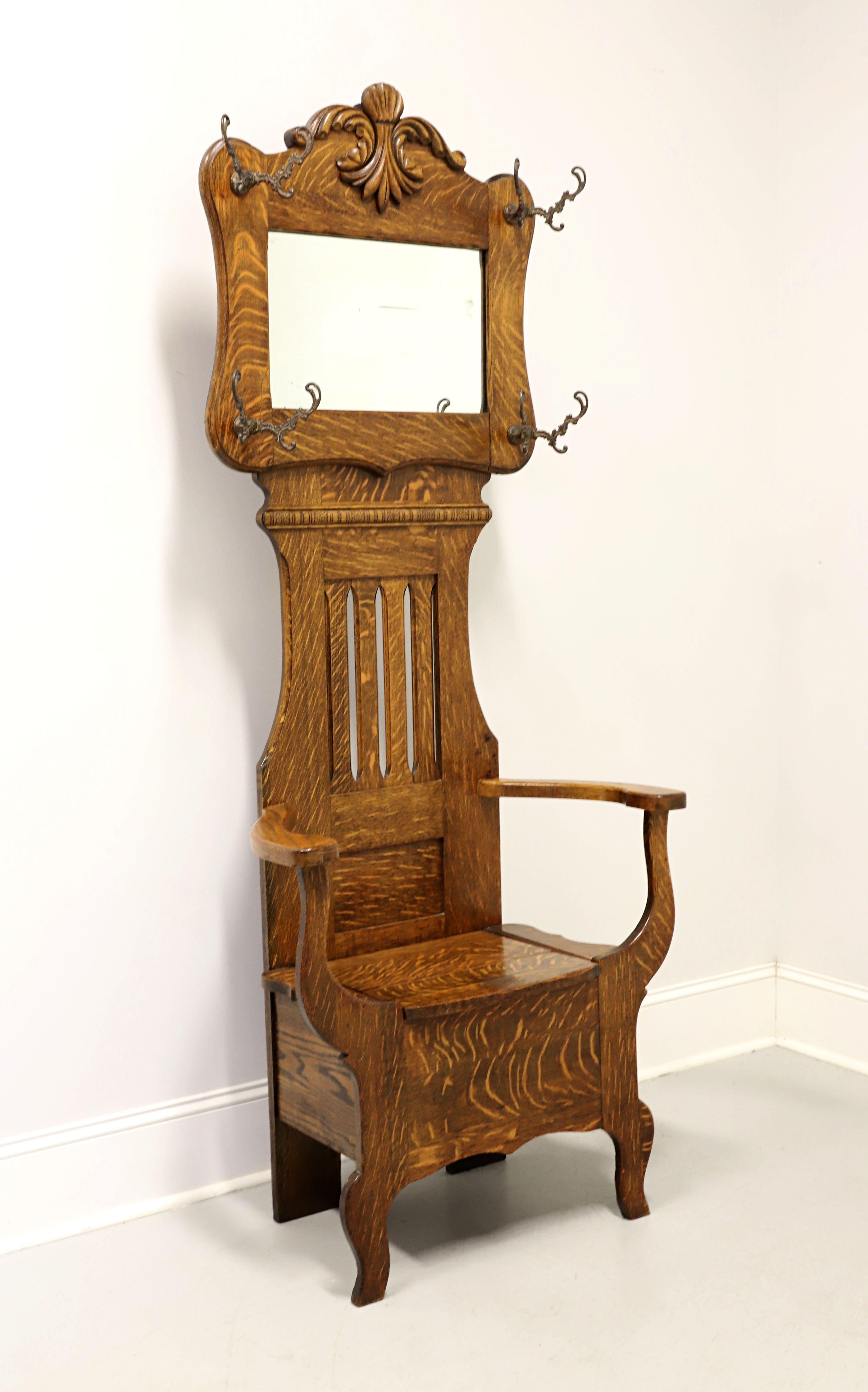An antique Victorian period hall tree with mirror and chair bench, unbranded. Solid tiger oak with brass hooks and mirror. Features decoratively carved framed mirror at top with garment hooks, decorative open carved backrest providing mirror