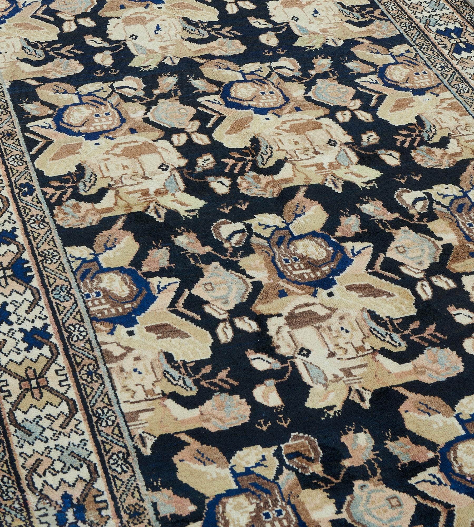 This antique, circa 1910, Malayer runner has a charcoal-blue field with and overall design of ivory, light blue and shaded fox-brown floral bouquets and floral motifs, in an ivory border of angular palmettes and paired angular flowerheads between