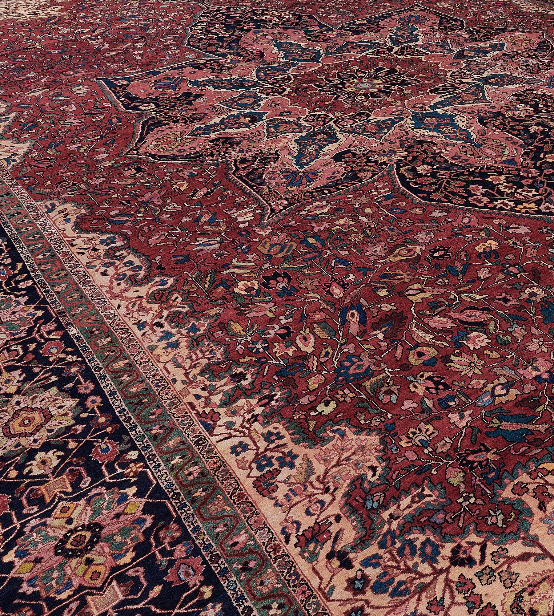 This antique, circa 1910, Fereghan rug has a brick-red field with a vase motif at each end issuing a delicate polychrome floral and leafy vine around a central indigo-blue and shaded pink cusped lozenge medallion, a brick-red central floral lozenge