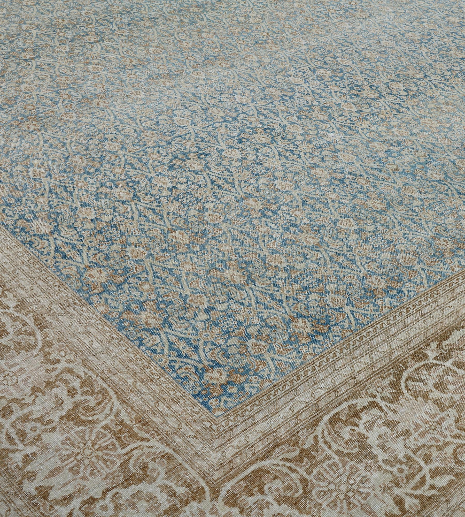 Questo antico tappeto Tabriz autentico, risalente al 1910 circa, ha un campo azzurro sfumato con un motivo herati avorio e marrone volpe, con un'ampia bordura marrone volpe sfumata con viti floreali avorio a scorrimento tra strisce floreali